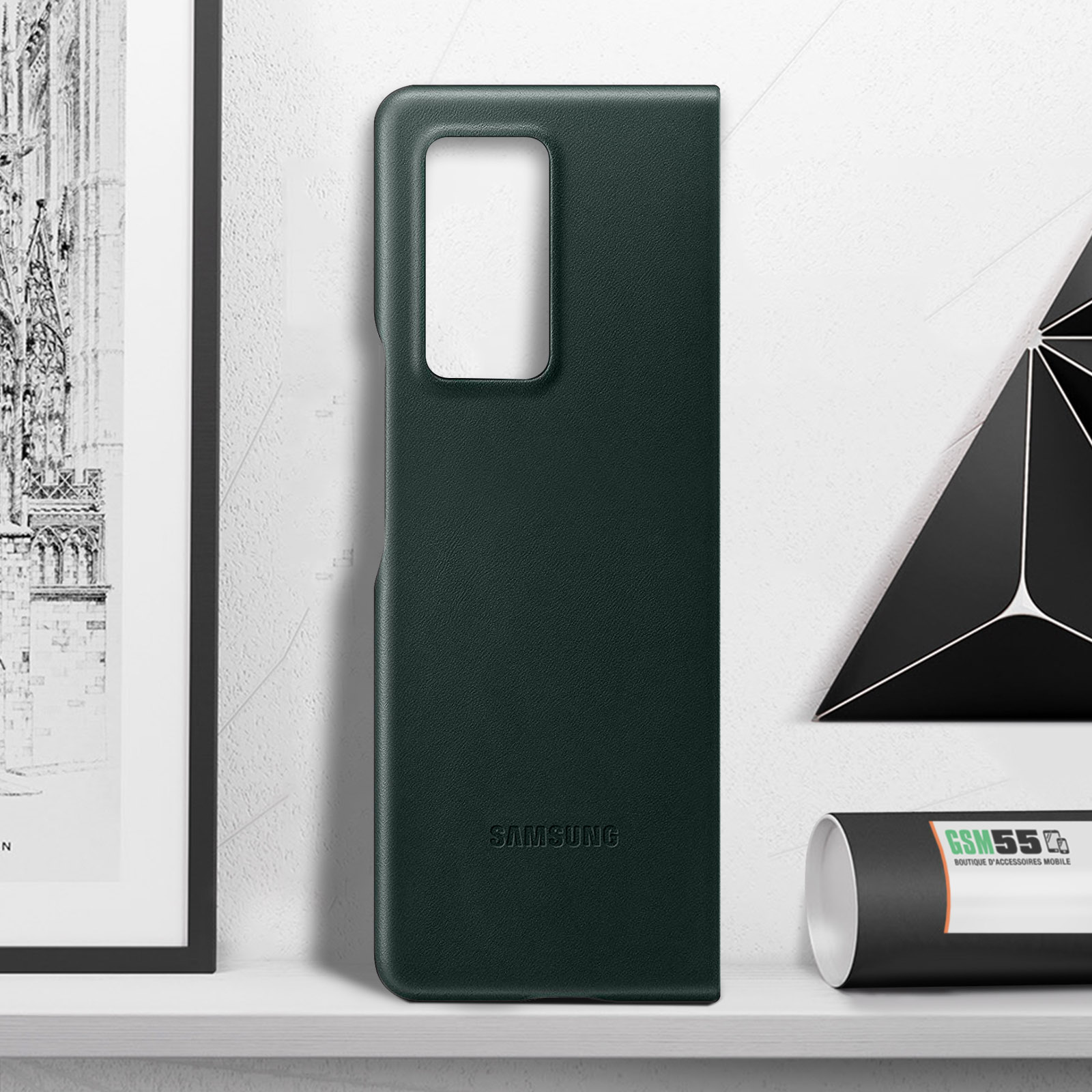 Una funda de teléfono verde de pie. La palabra 'SAMSUNG' es visible. Fondo: superficie blanca.