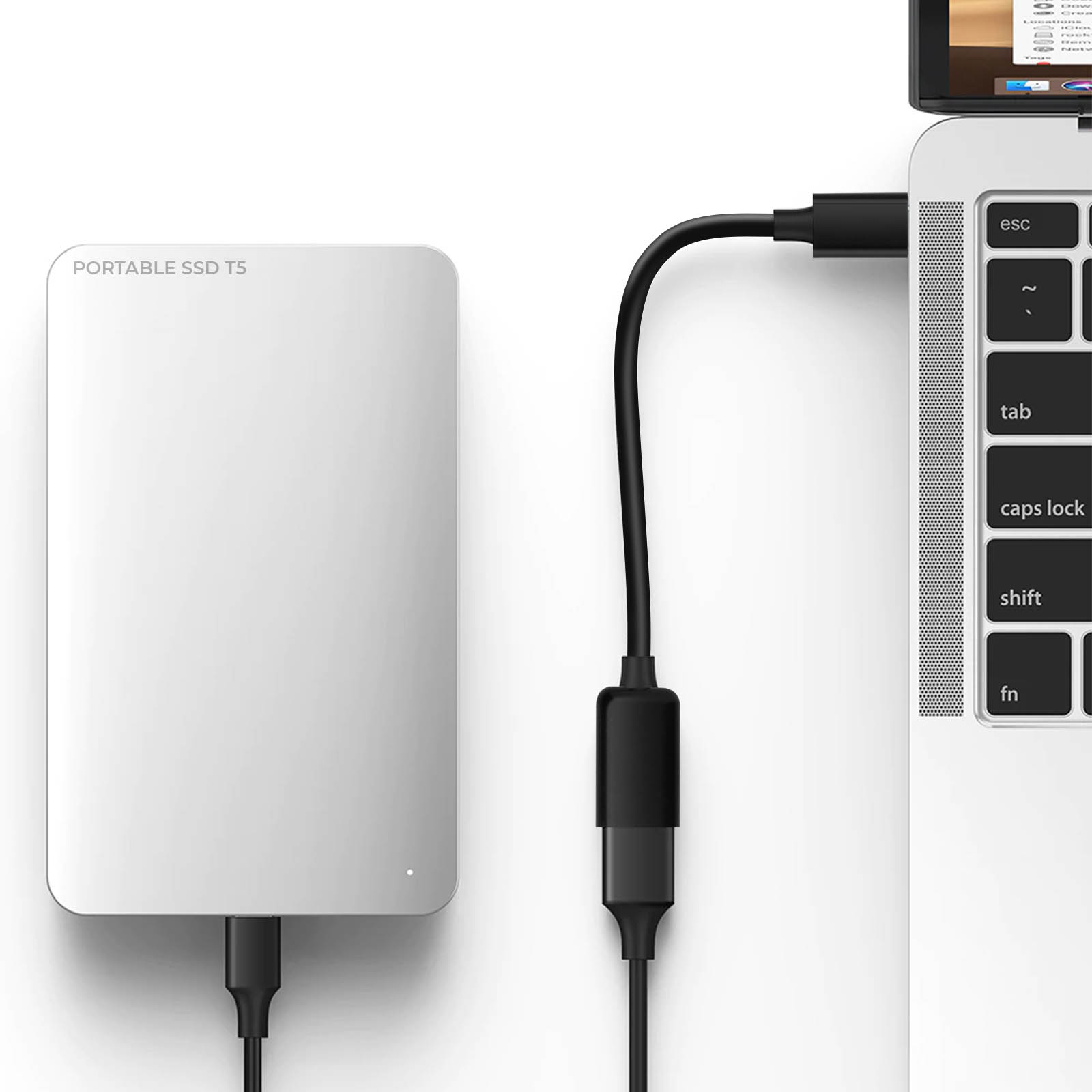 Un SSD portatile bianco è collegato a un laptop con un cavo nero.
