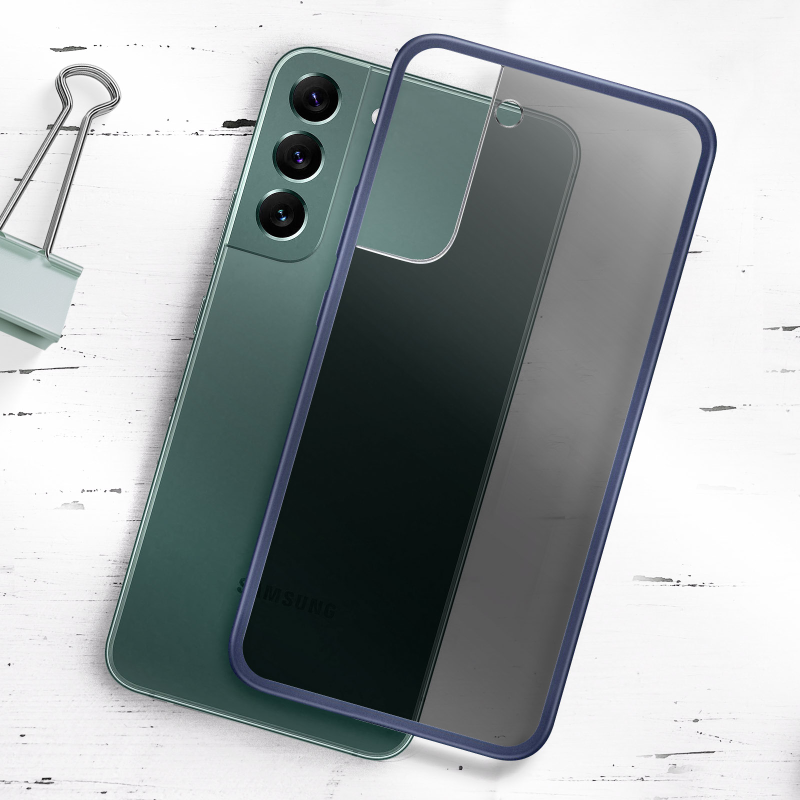 Groene telefoon met een blauwe hoes. Een paperclip ligt op de witte houten achtergrond.