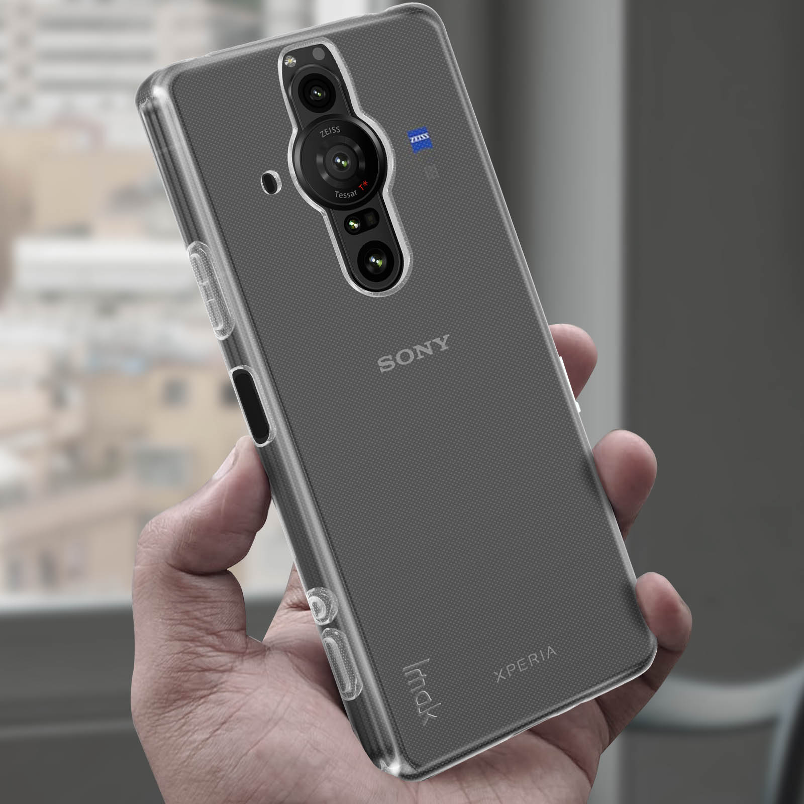 Telefono tenuto in mano, coperto da una custodia trasparente. Loghi Sony e Zeiss visibili.