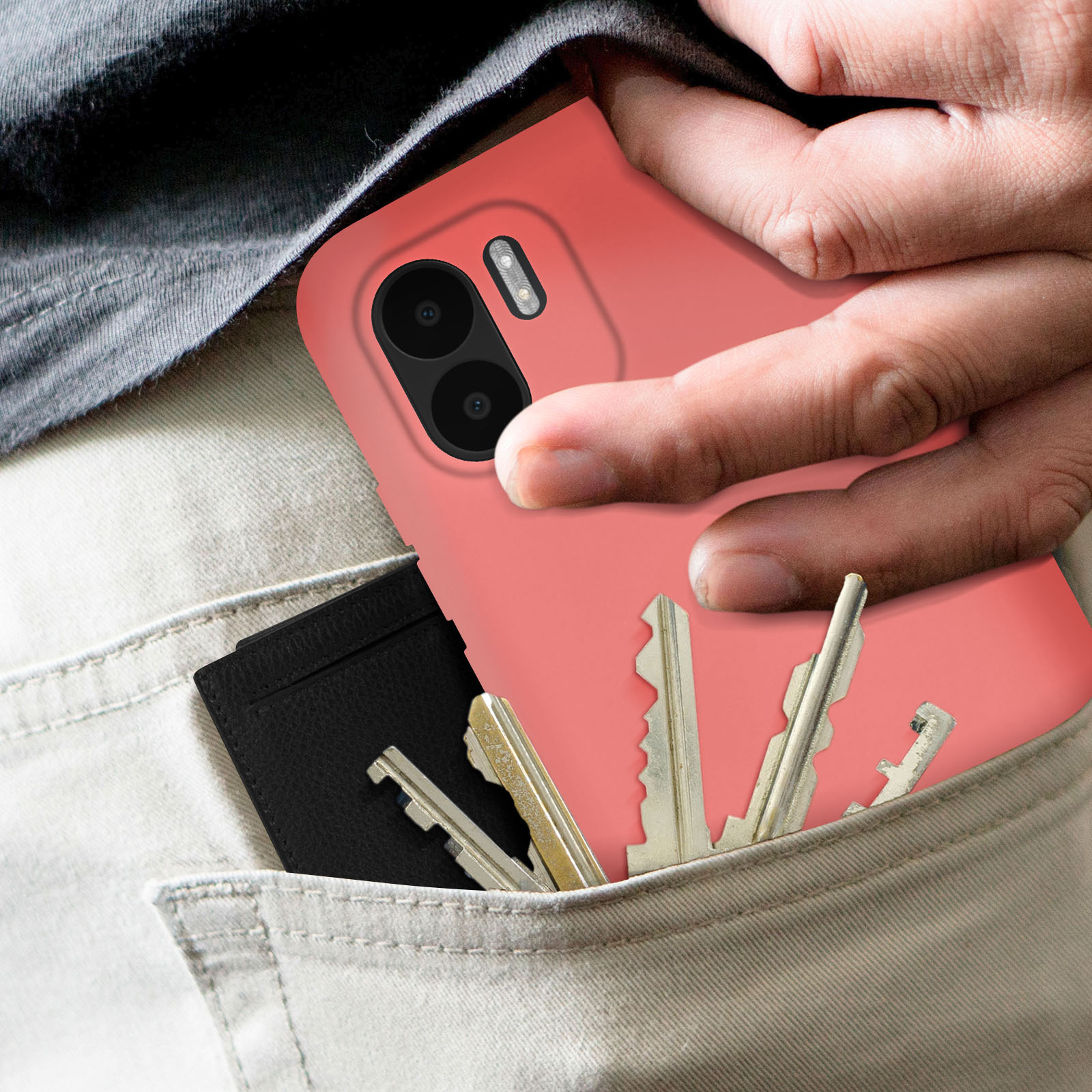 Een hand houdt een koraalroze telefoon met een zwart hoesje vast. Sleutels en een kaart in een zak.