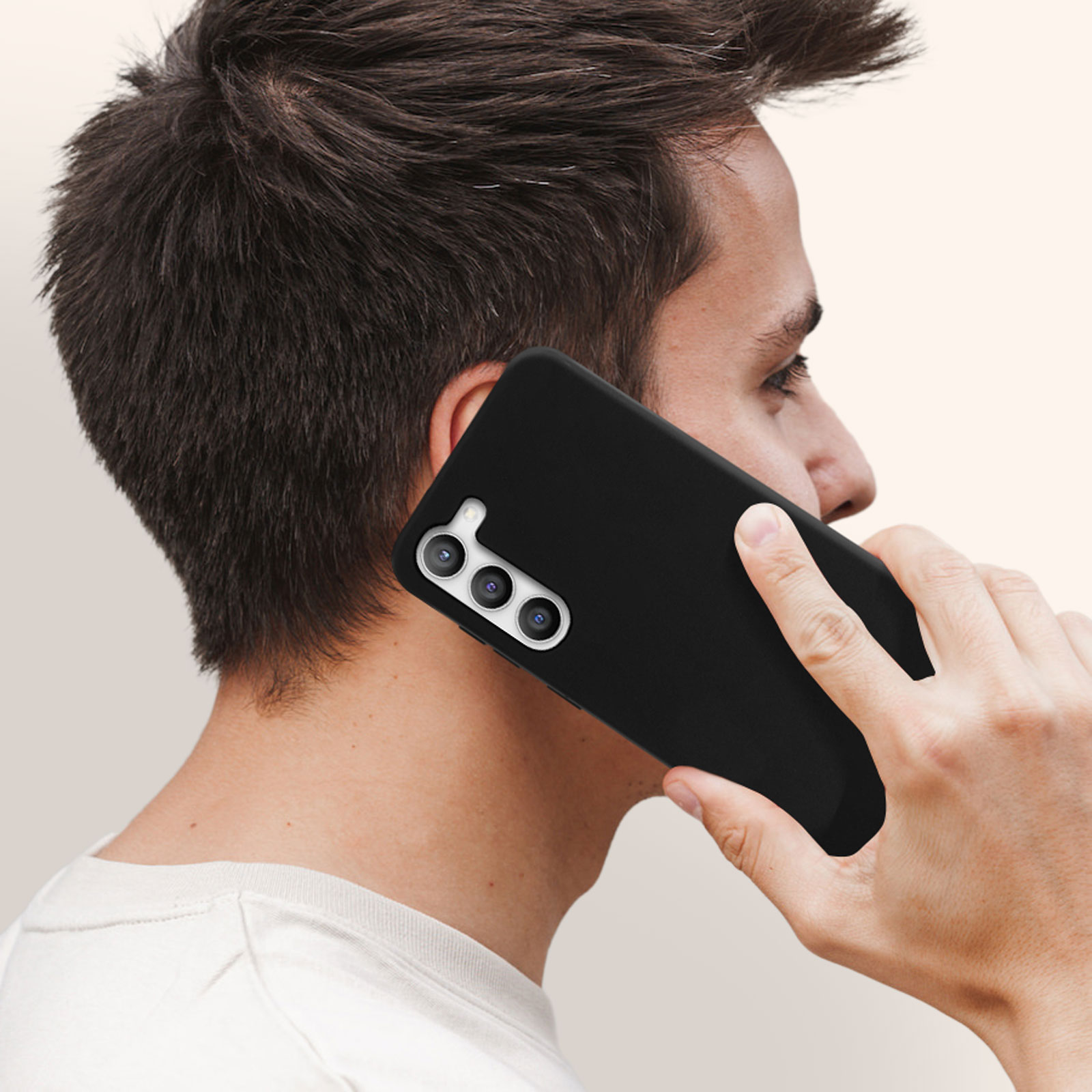 Homme tenant un téléphone noir avec une coque noire près de son oreille. Caméra focalisée.