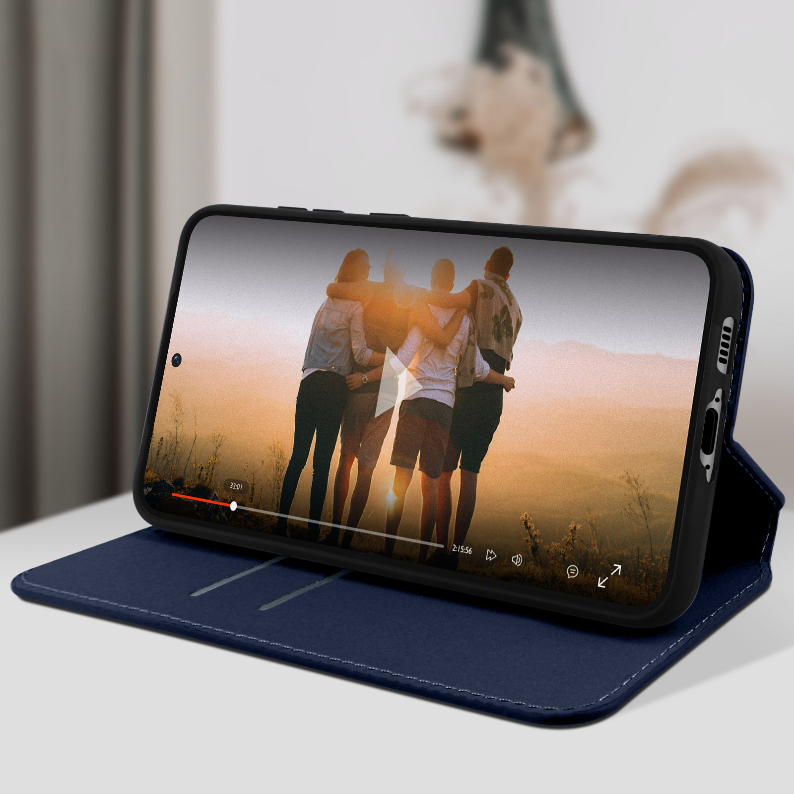 Un téléphone dans un étui portefeuille bleu, affichant une vidéo de personnes au coucher du soleil.