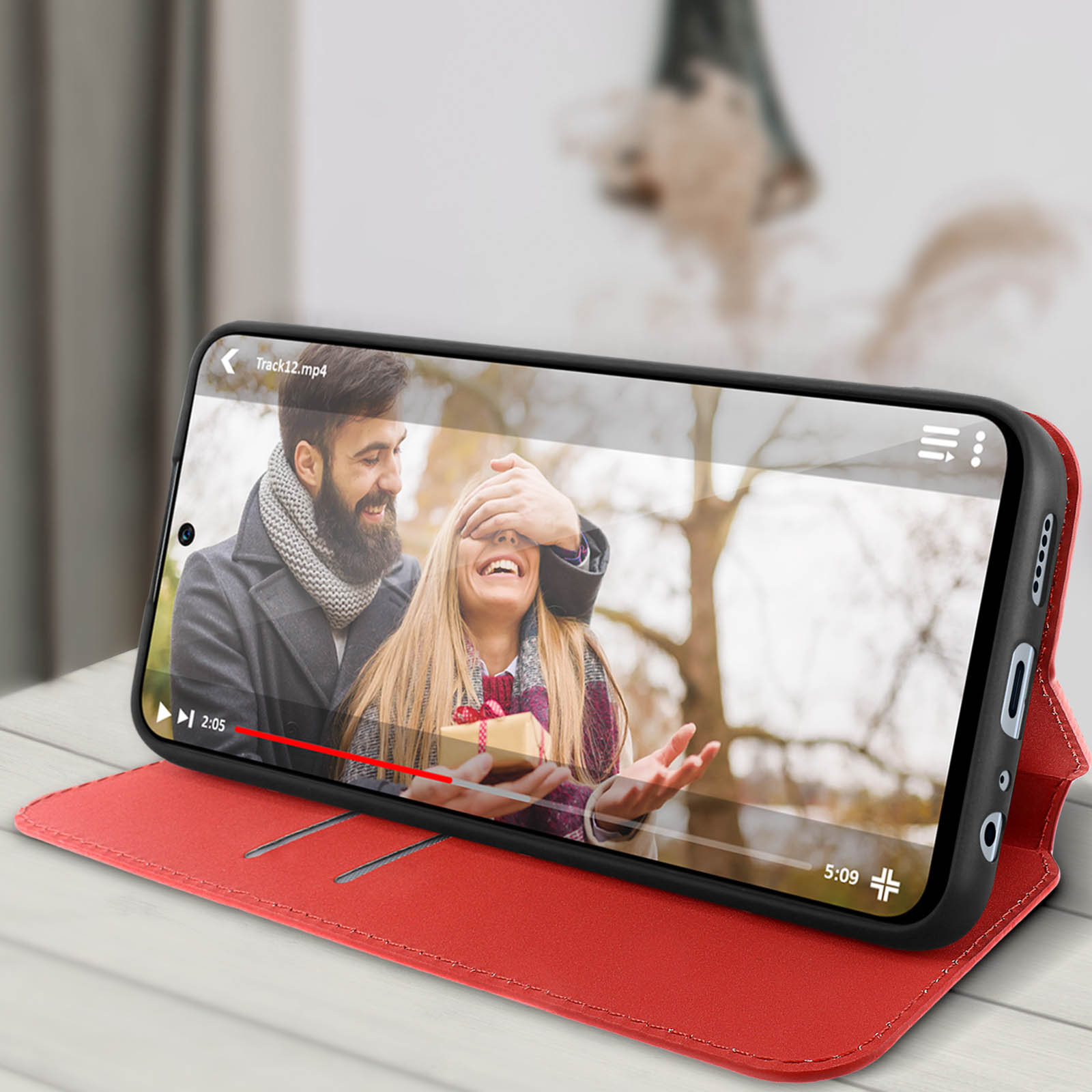 Téléphone dans un étui rouge, montrant une vidéo d'un couple avec un cadeau.