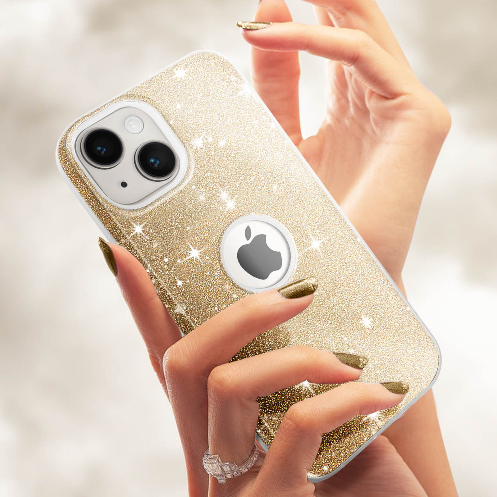 Eine Hand hält eine goldfarbene Glitzer-iPhone-Hülle. Das Telefon hat ein silbernes Apple-Logo.