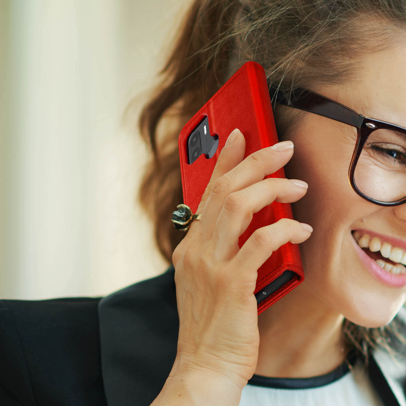 Donna al telefono, con custodia rossa. Indossa occhiali e un anello. Sfondo bianco.