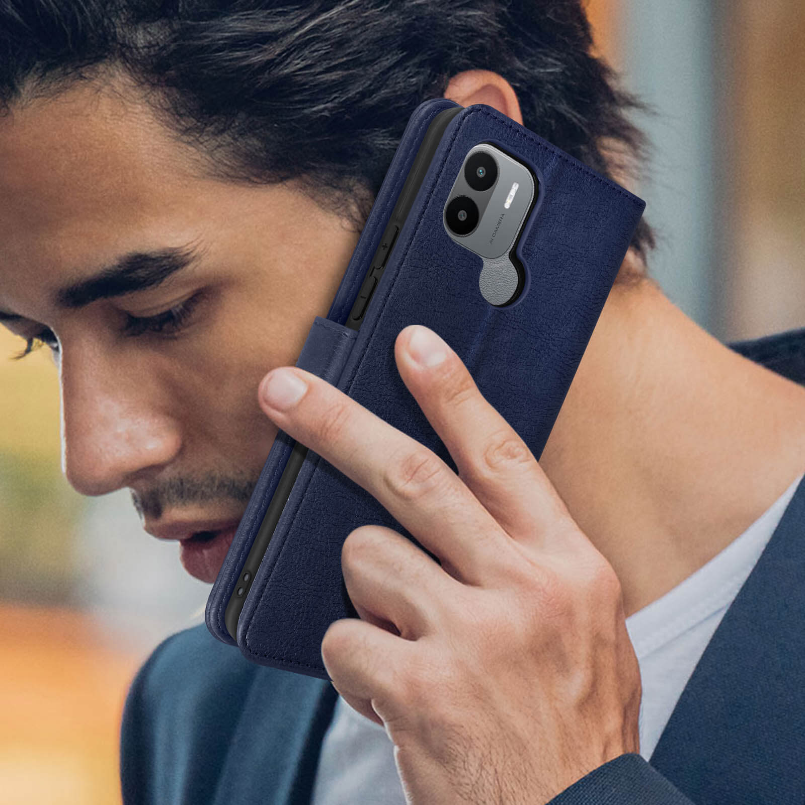 Uomo che tiene un telefono all'orecchio. Il telefono è in una custodia blu.
