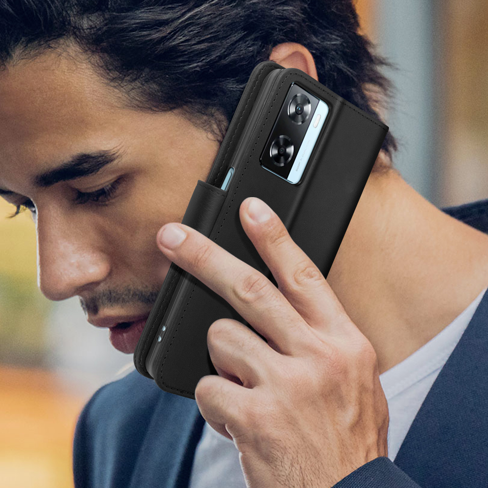 Un uomo tiene un telefono nero in una custodia vicino all'orecchio, con lo sguardo concentrato.