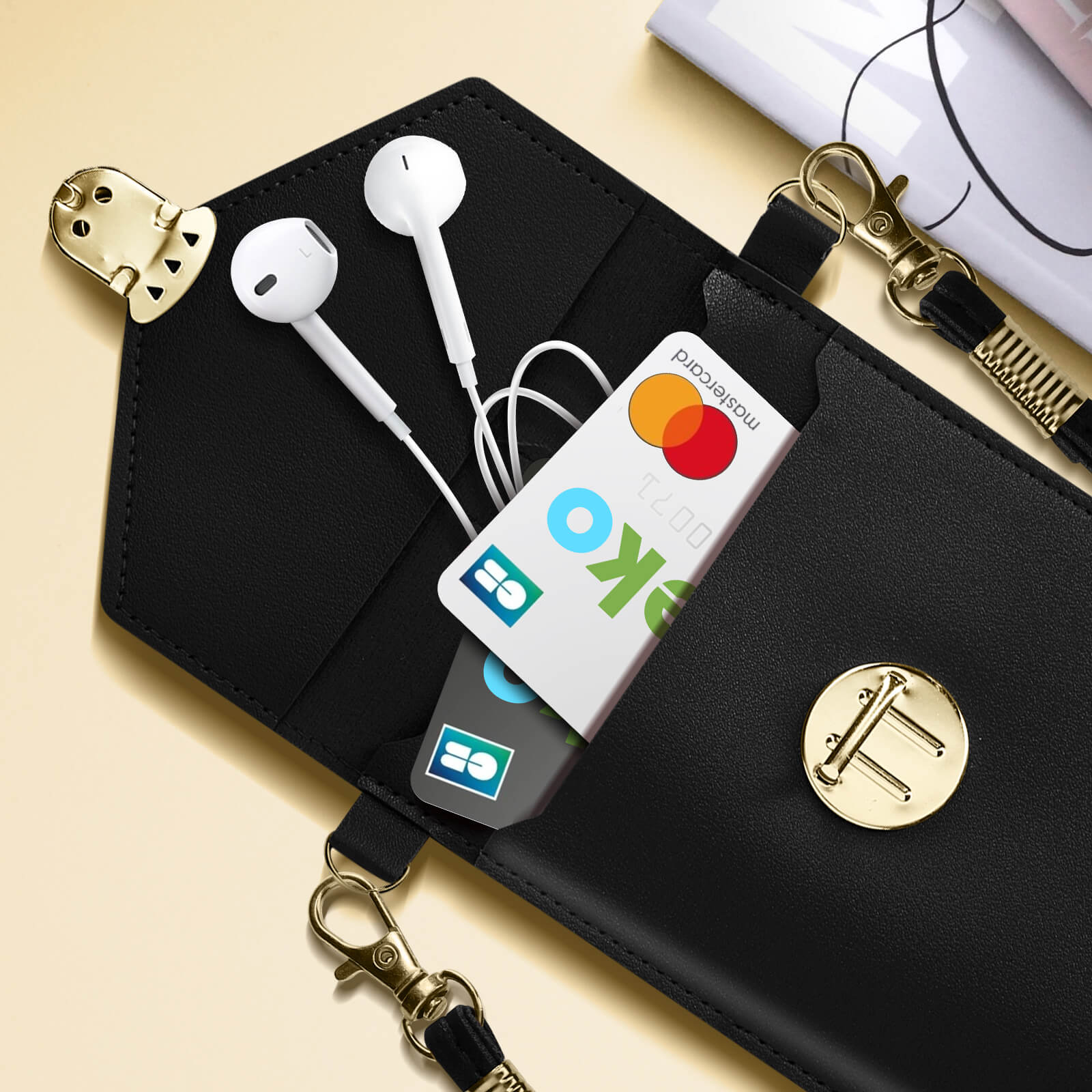 Custodia per telefono nera con auricolari e carta di credito. Chiusure e catena dorate.