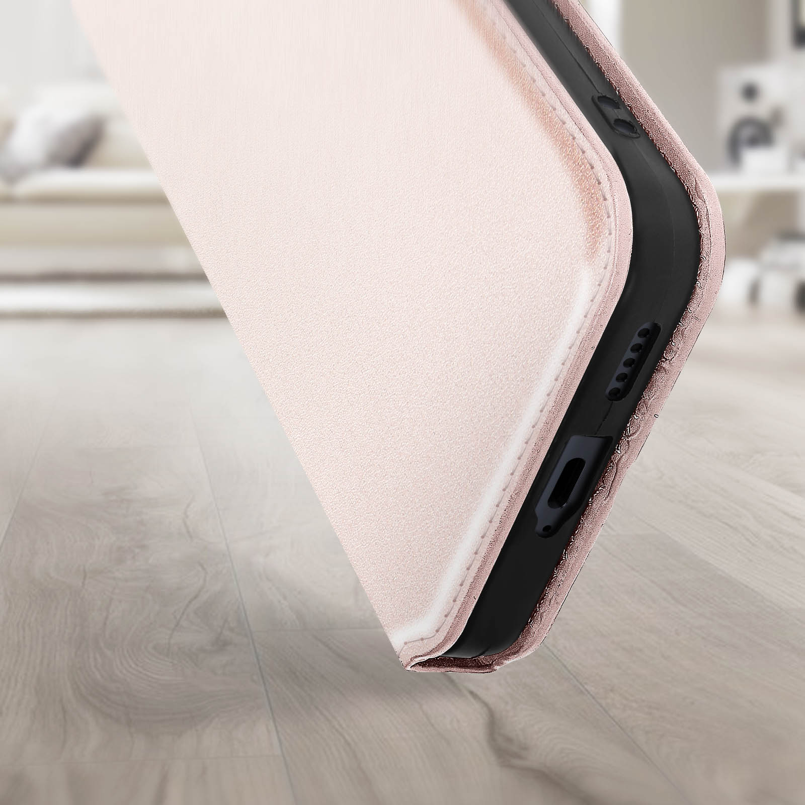 Custodia per telefono rosa, aperta e che mostra il telefono. È su un pavimento di legno. Lo sfondo è sfocato.