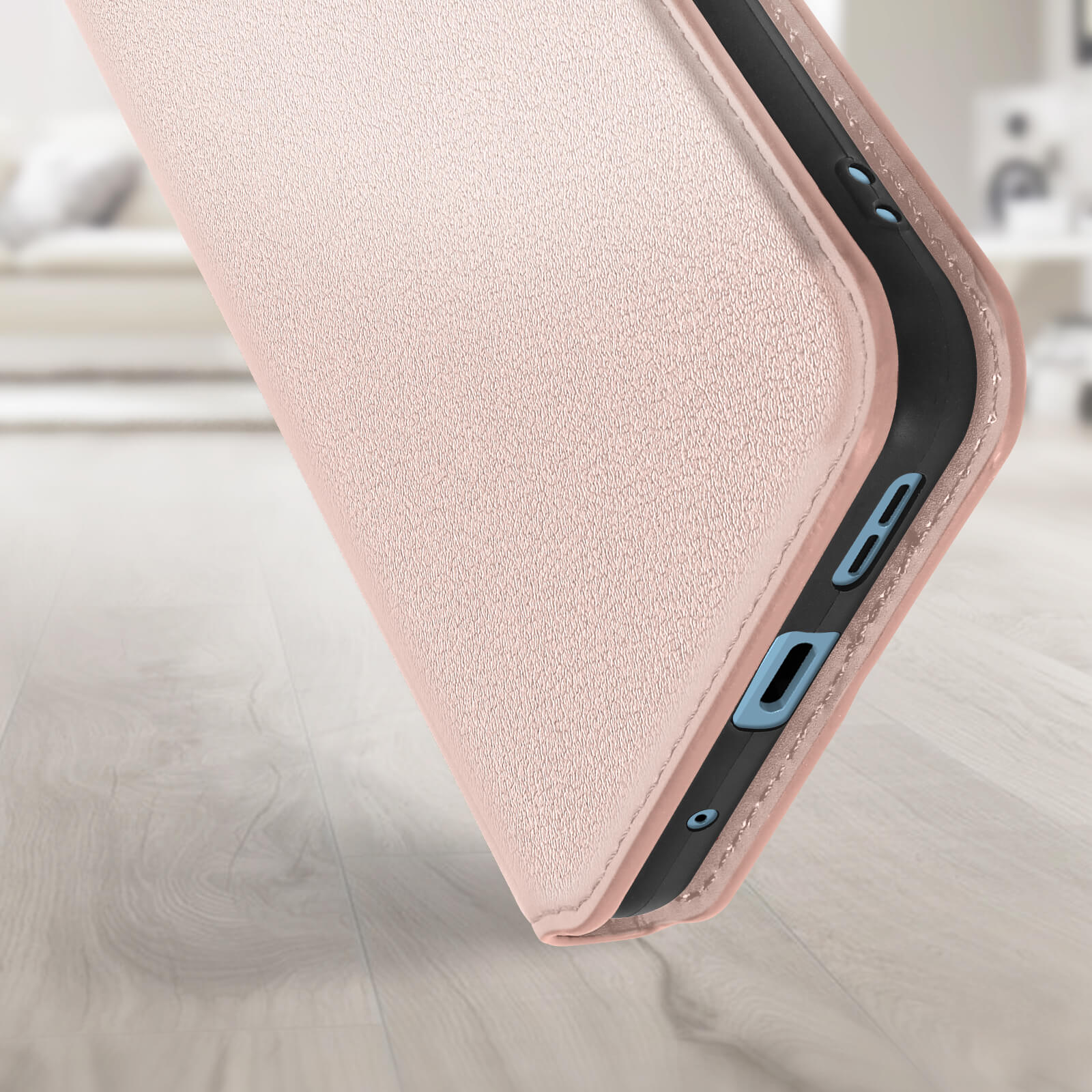 Un primo piano di una custodia rosa per telefono, che mostra il lato con ritagli per pulsanti e porte. Su legno.