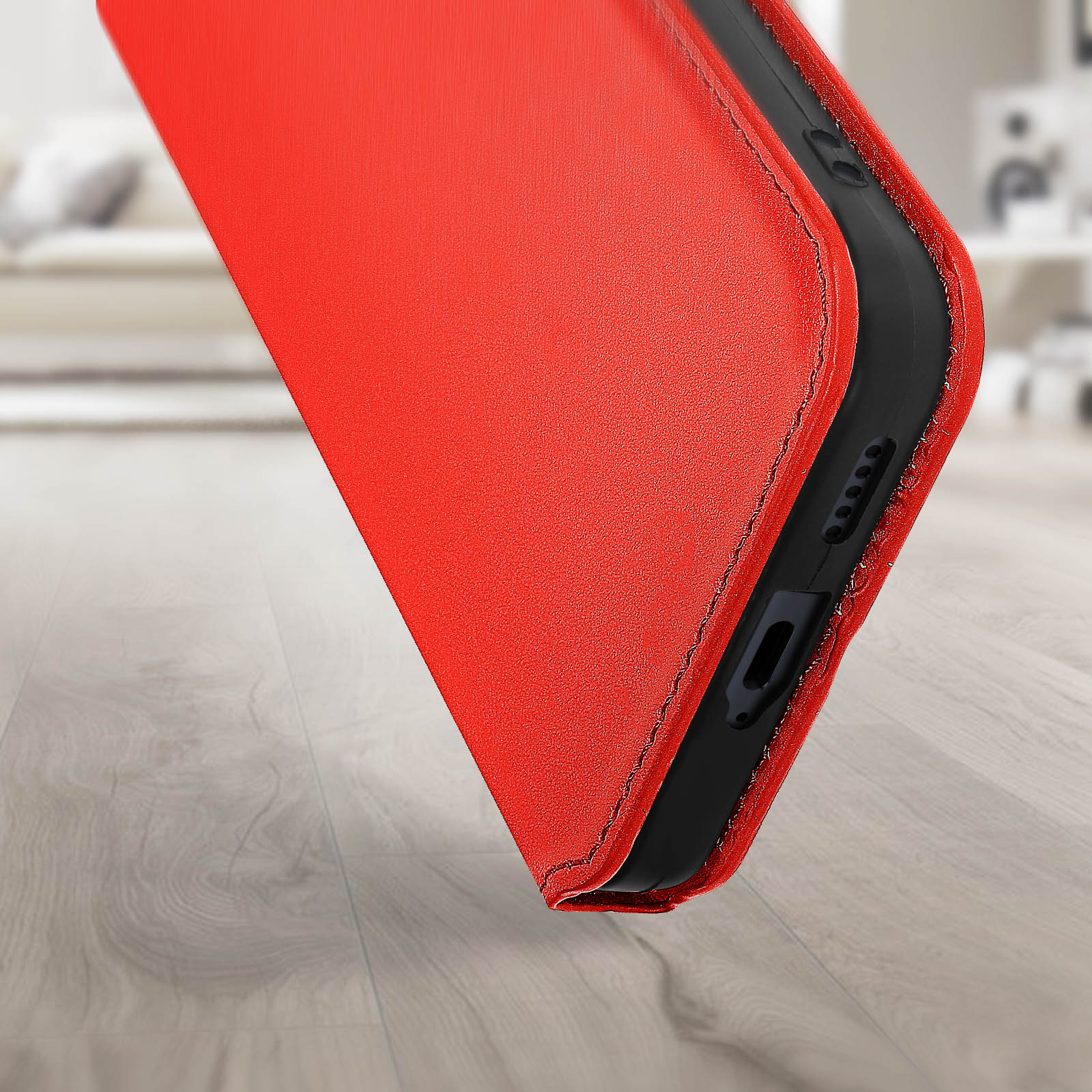 Custodia rossa per telefono, angolata su superficie in legno. Dettagli neri visibili.