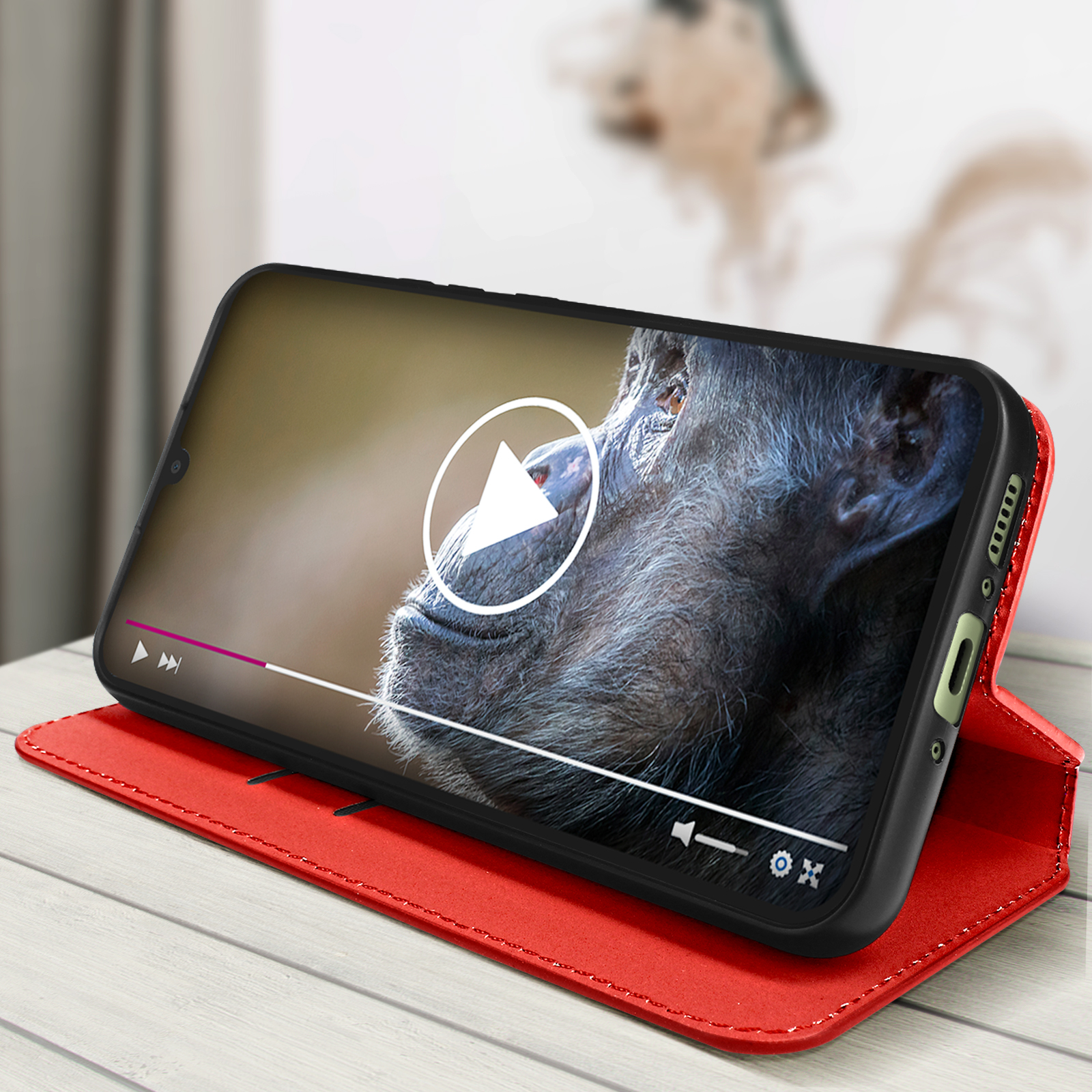 Custodia per telefono rossa aperta. Il telefono è all'interno della custodia, mostrando un video di uno scimpanzé sullo schermo.