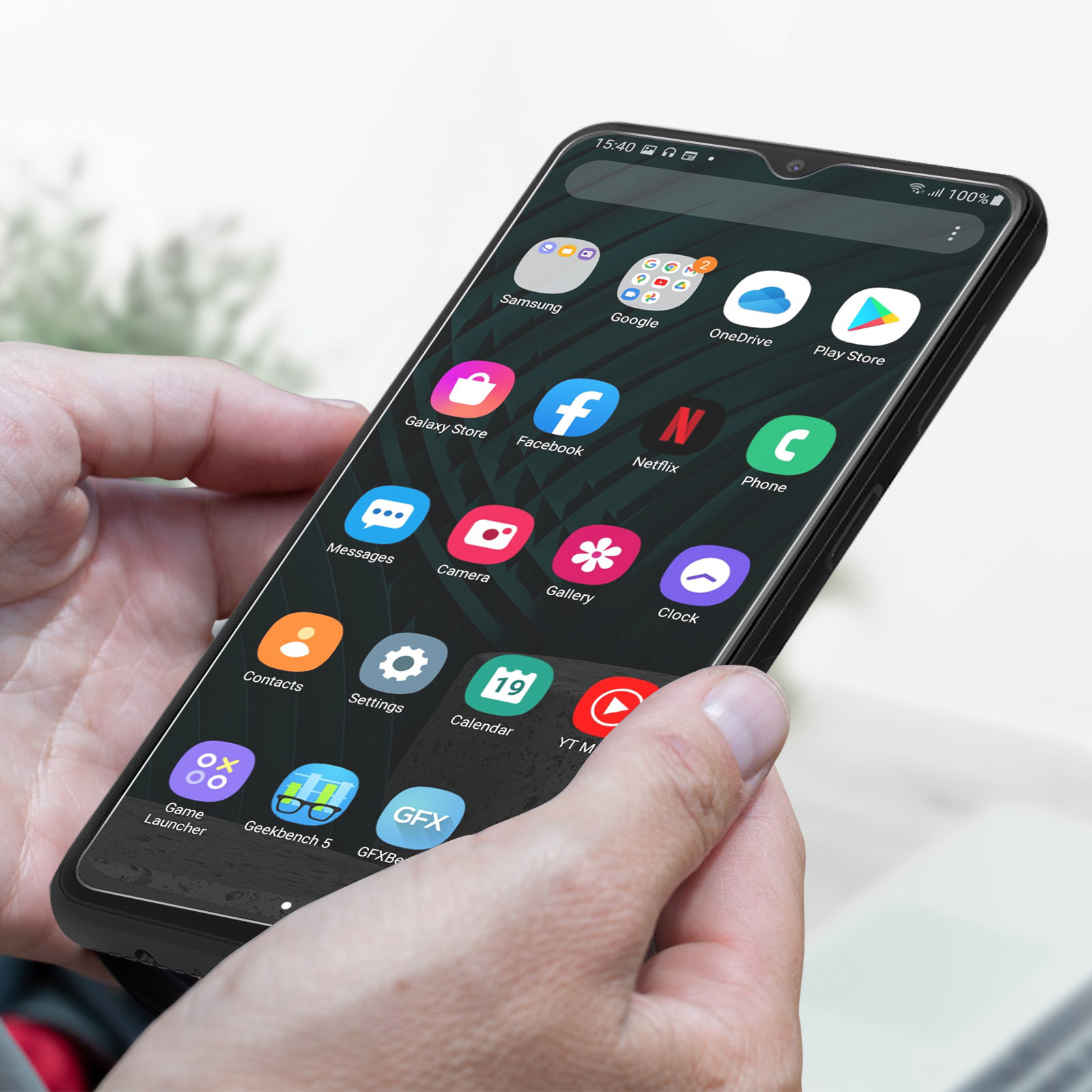 Handen van een persoon die een telefoon vasthoudt met app-iconen en een volledig scherm.