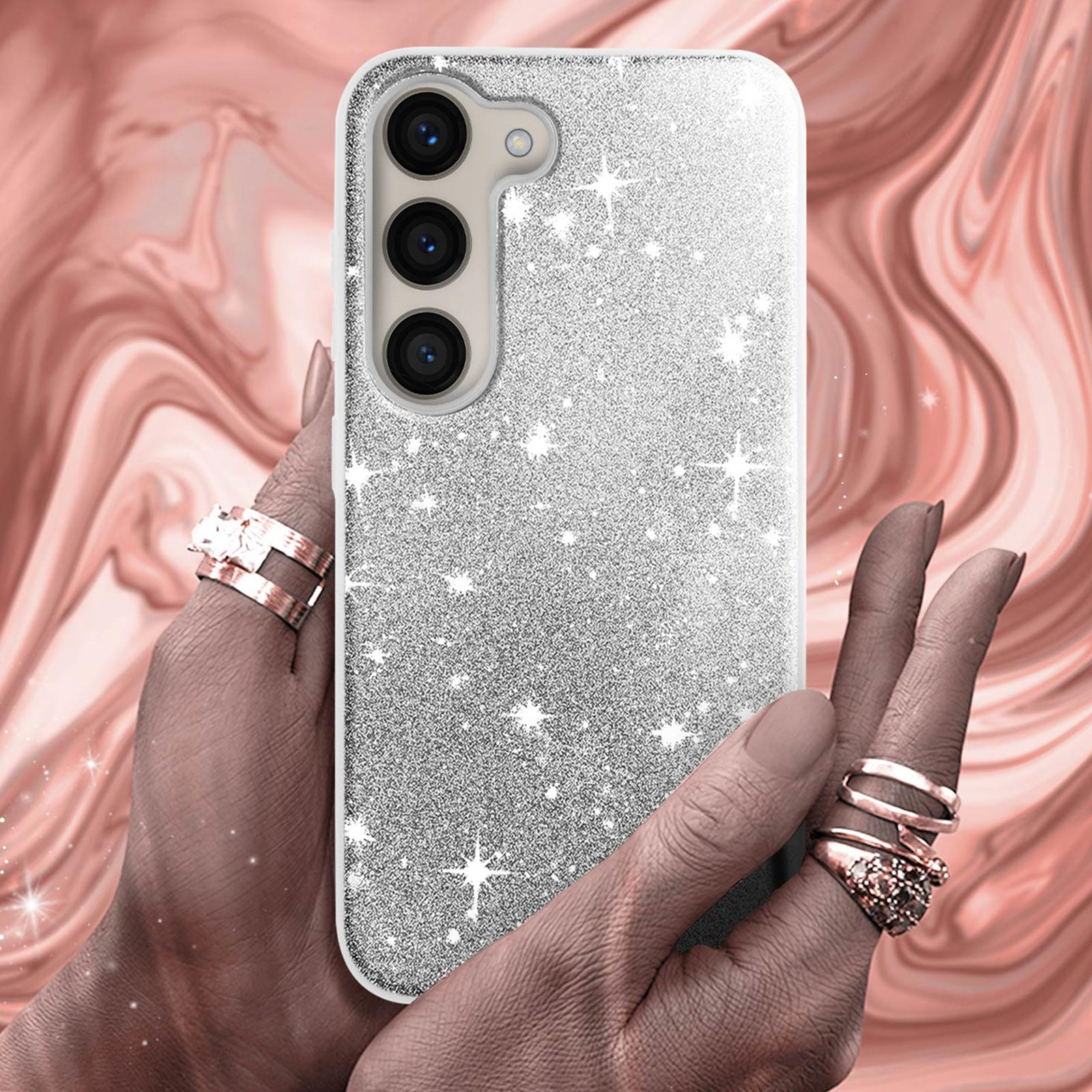 Una custodia per telefono argentata con glitter tenuta in mano con anelli. Sfondo con motivo rosa a spirale.