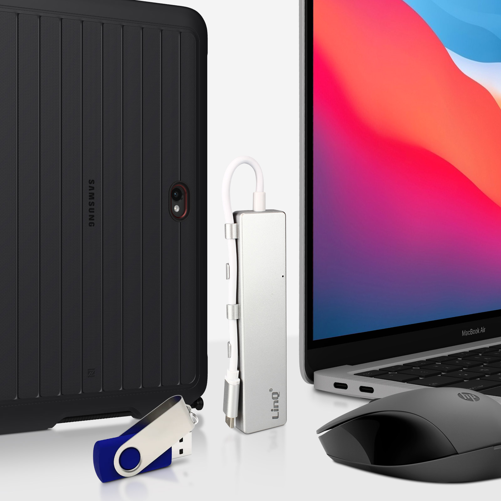 Un laptop, una custodia nera per tablet, una chiavetta USB e un mouse su un tavolo.
