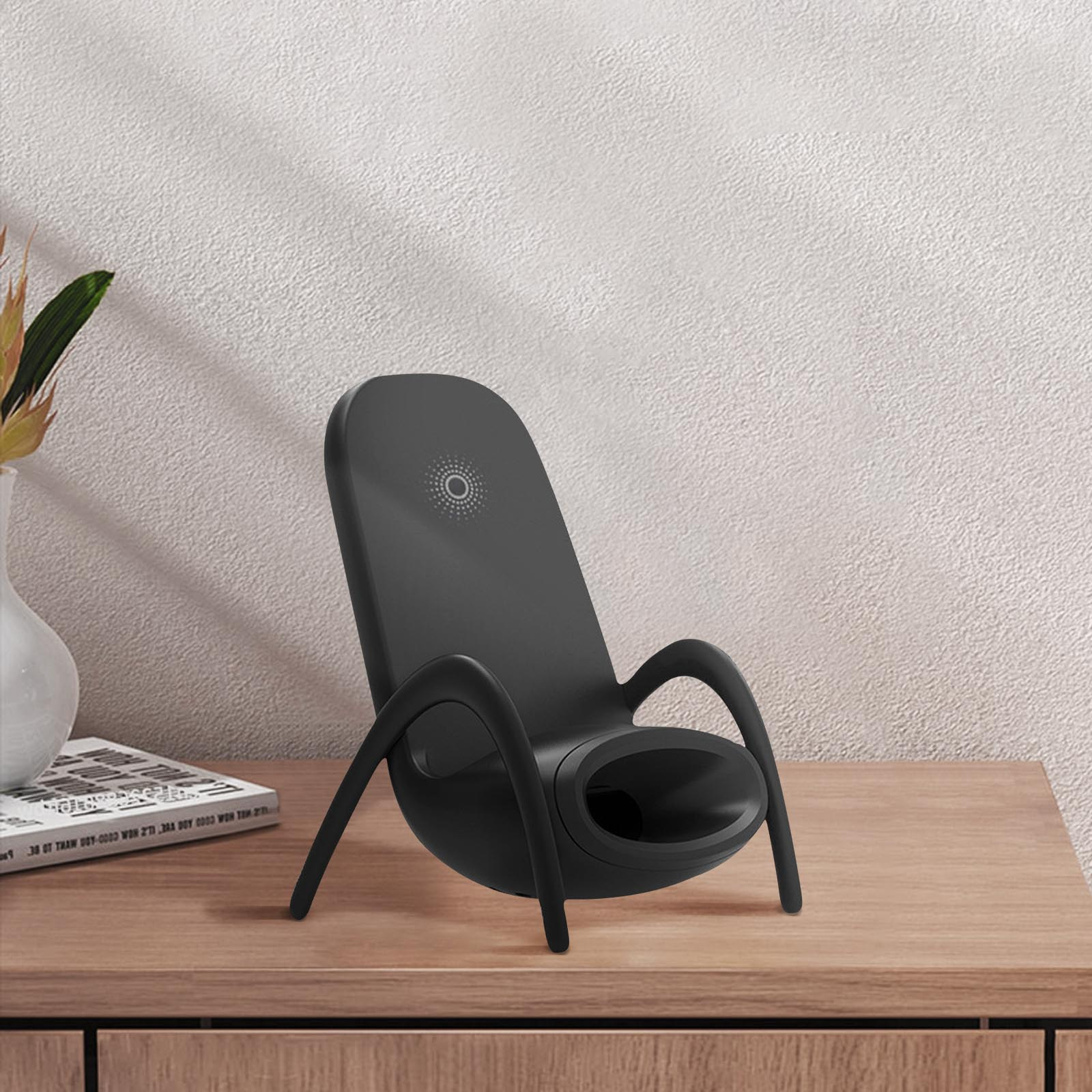 Un cargador inalámbrico negro, con la parte trasera curvada y un agujero en la parte delantera. Está sobre una mesa de madera.