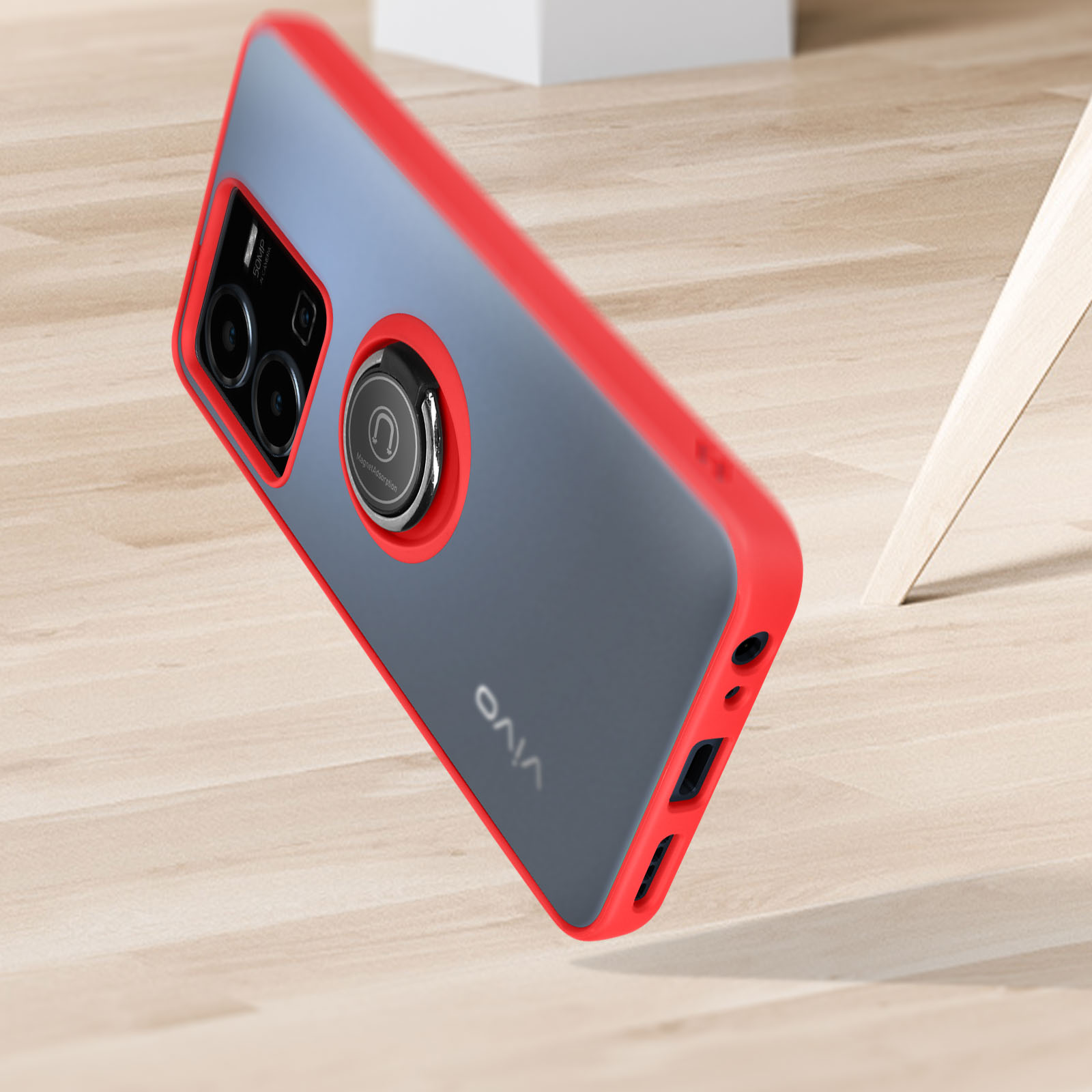 Una custodia per telefono in aria, rossa e grigia, con un anello. Sta cadendo.