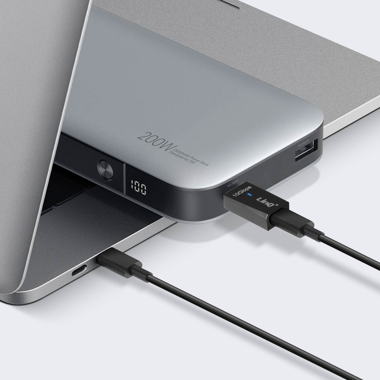 Laptop con power bank collegato tramite cavo USB. Power bank mostra '200W' e '100'.