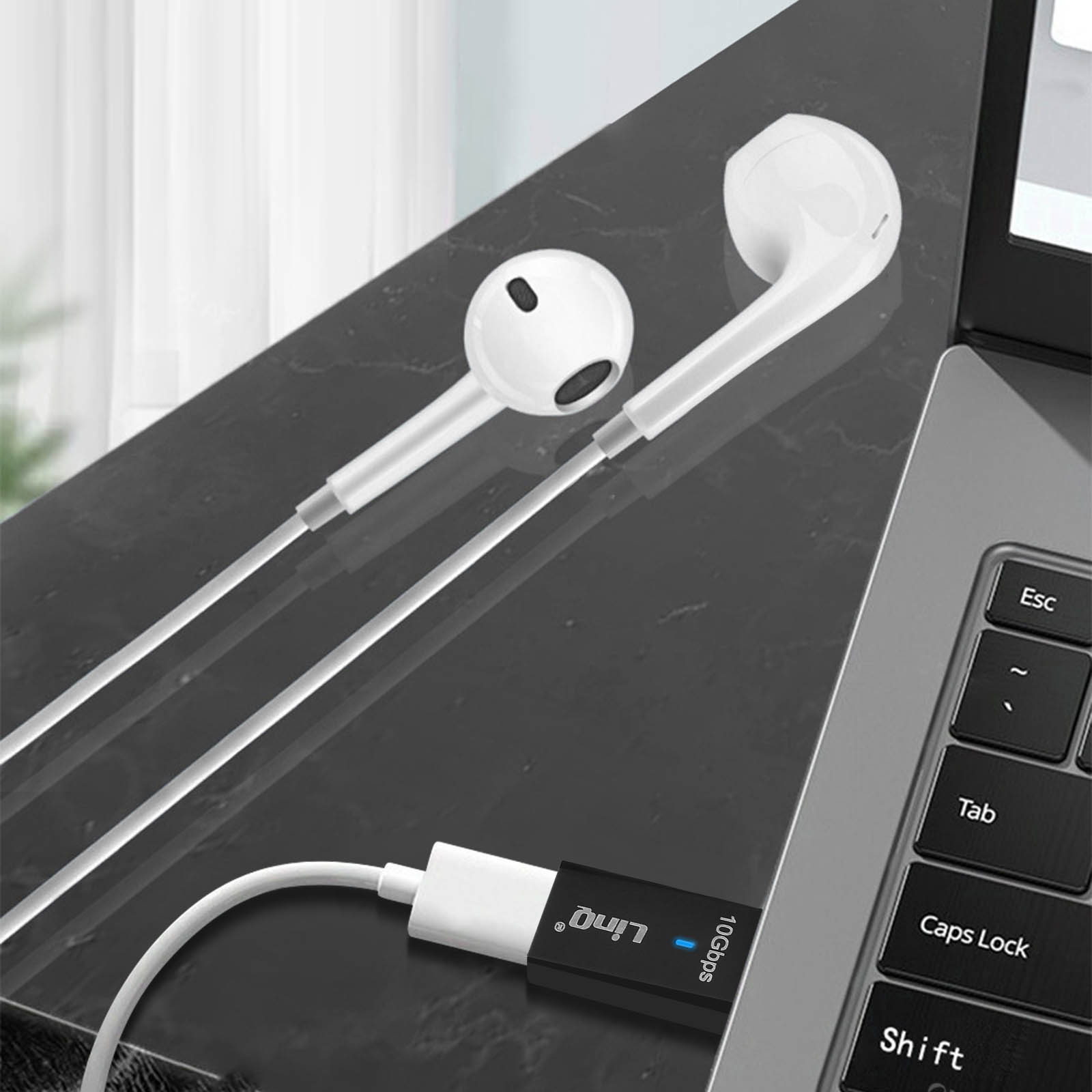 Auricolari bianchi e un adattatore nero collegati alla tastiera di un laptop.