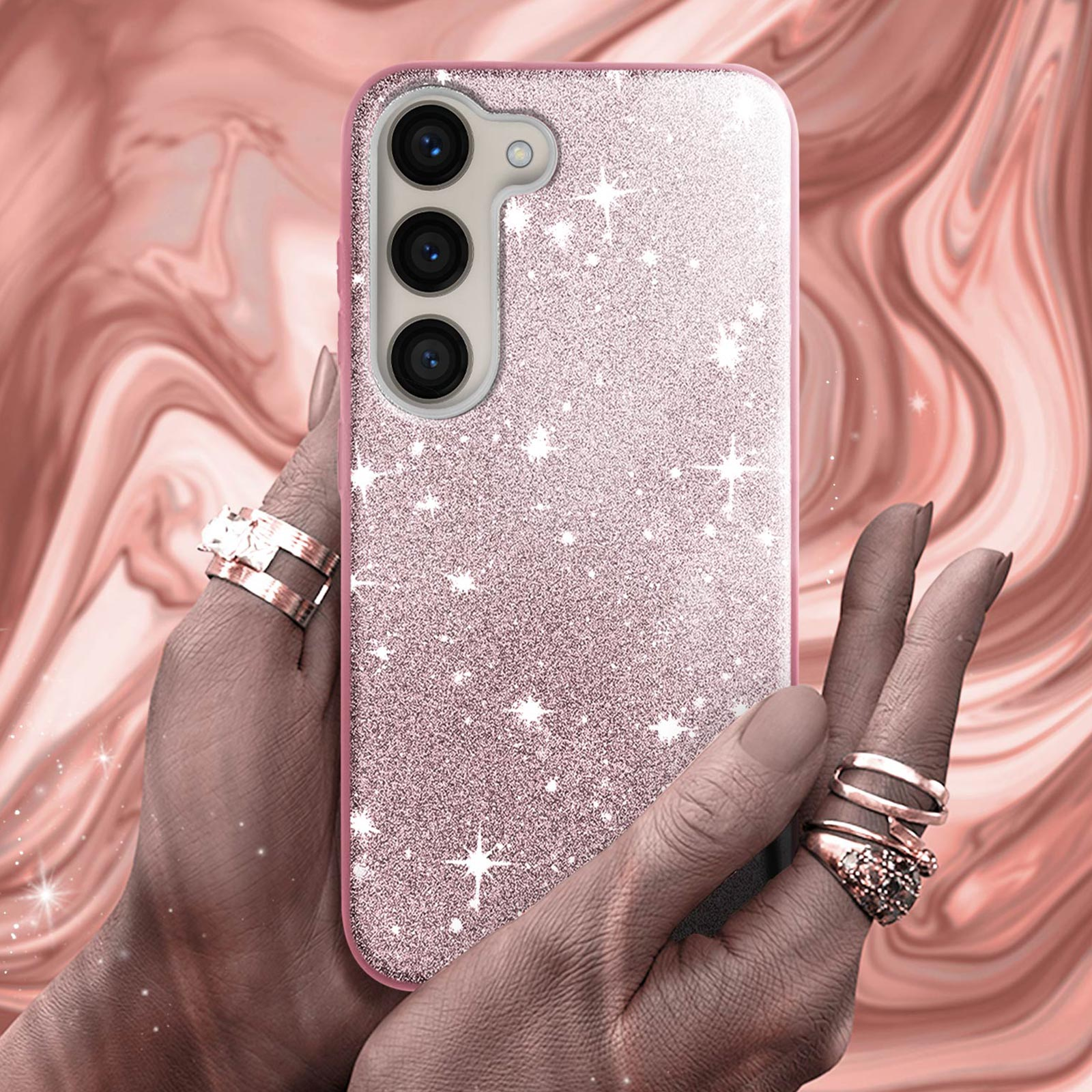Mani di donna che tengono una custodia per telefono rosa glitterata con tre fotocamere e anelli.