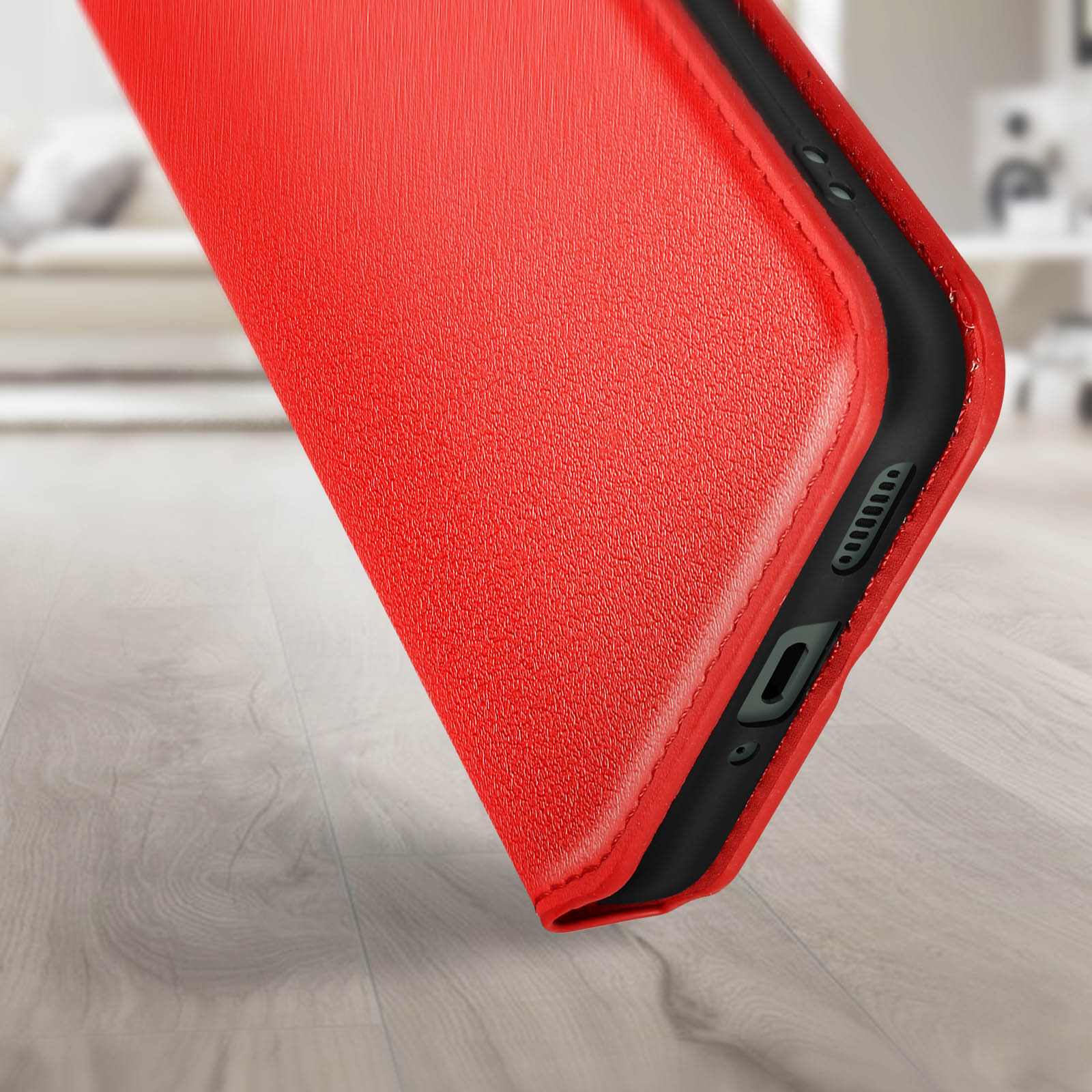 Custodia rossa per telefono su pavimento in legno. Bordo nero e porta fotocamera visibili.