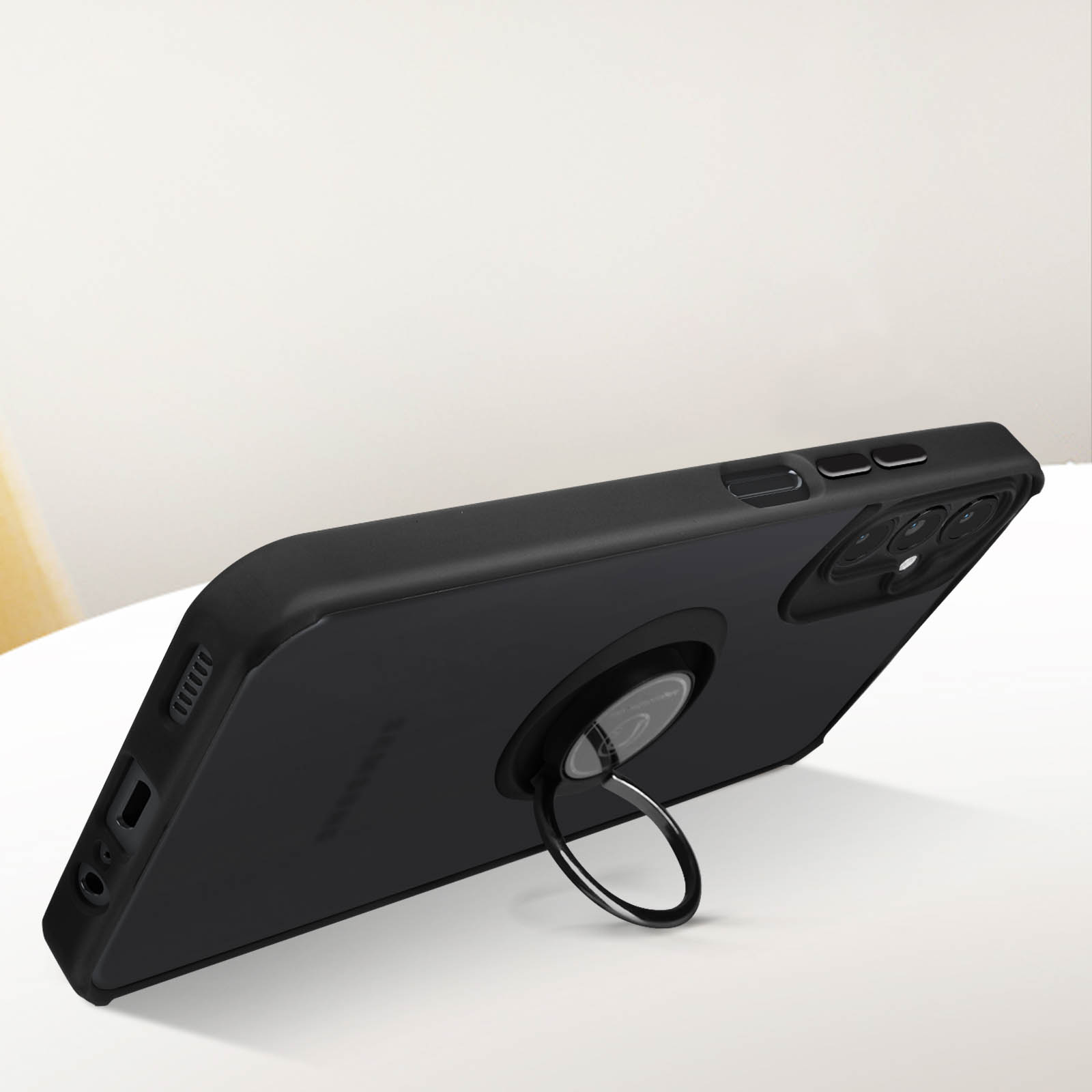 Zwarte telefoonhoes met ringhouder. Ligt op een wit oppervlak, met een vage achtergrond.