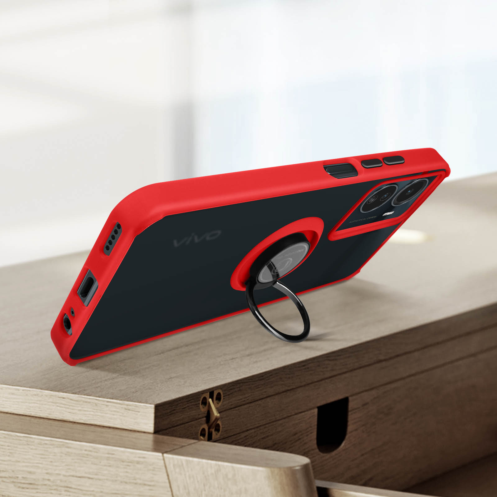 Una custodia per telefono rossa e nera con supporto ad anello è su una superficie di legno. Il telefono è angolato.