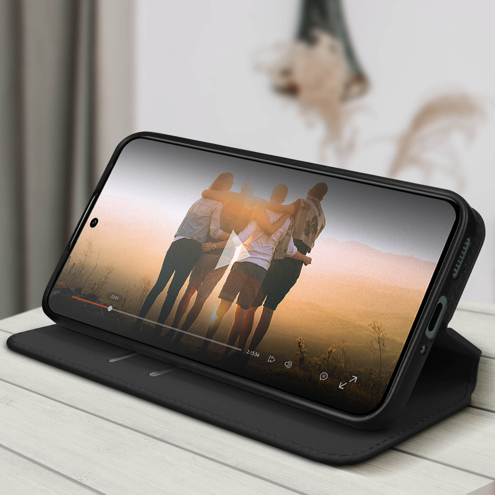 Ein Telefon, das ein Video anzeigt, in einem Gehäuse, ist auf einer Holzoberfläche geöffnet, mit unscharfem Hintergrund.