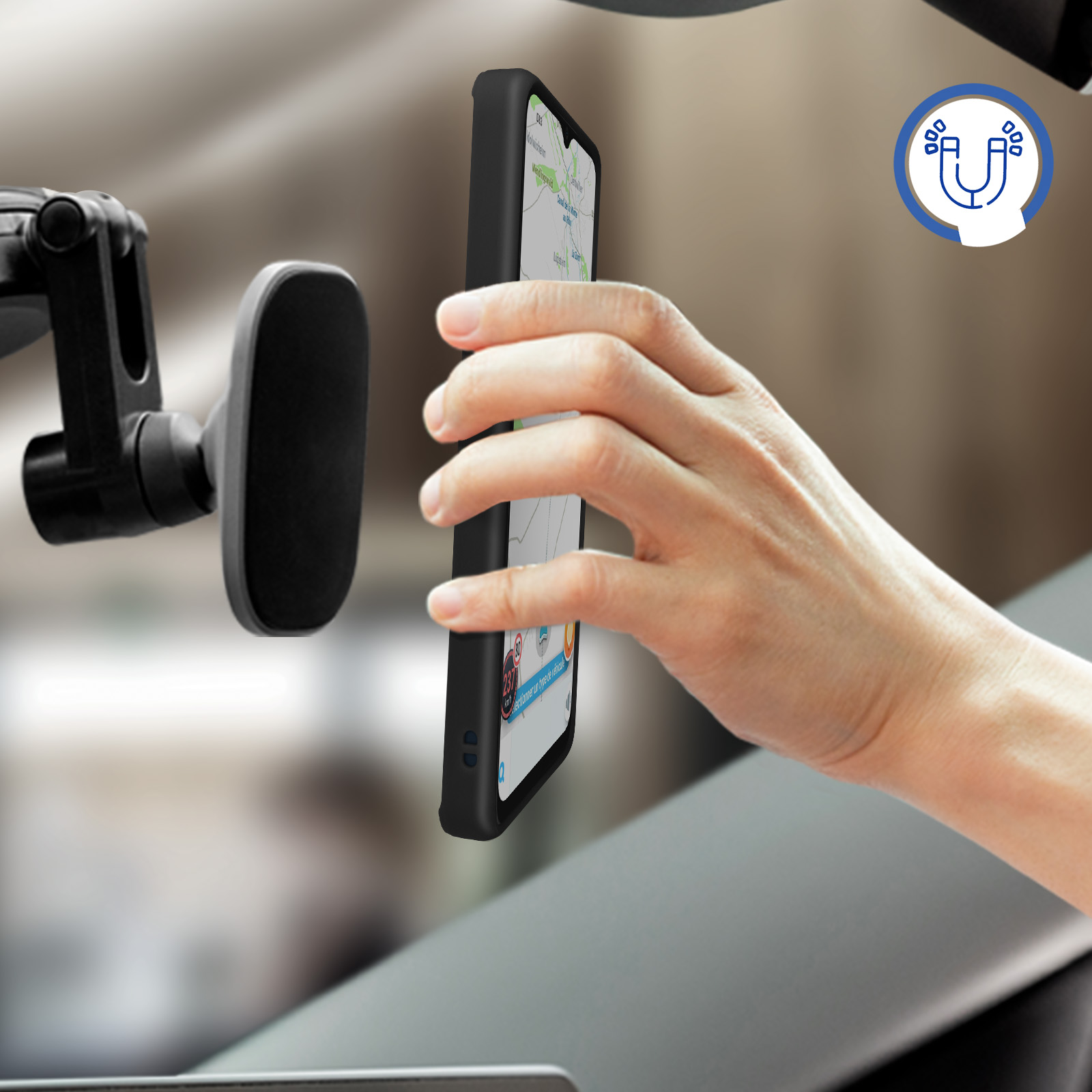 Una mano tiene un telefono in una custodia nera vicino al cruscotto di un'auto. Un simbolo di magnete è presente.