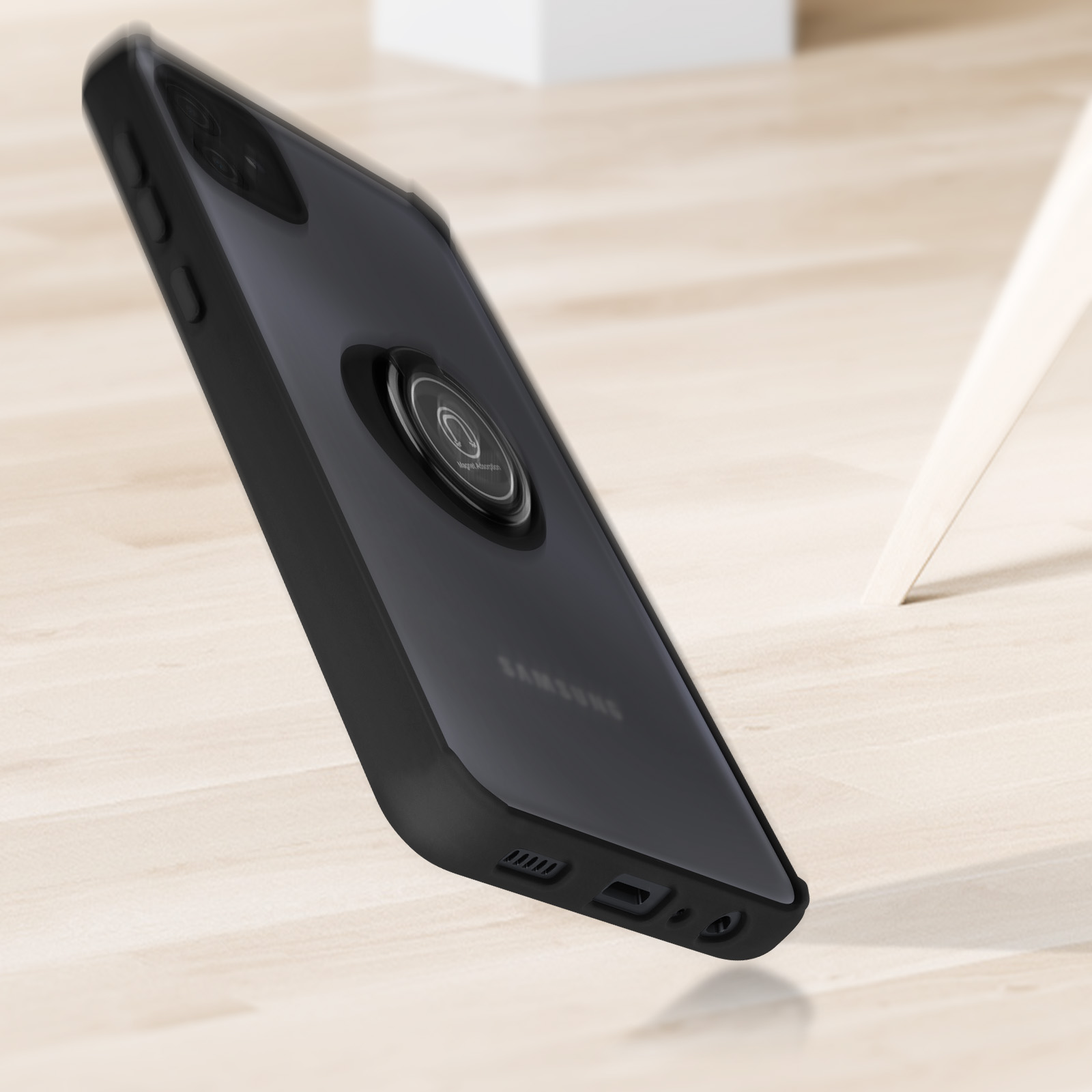 Una custodia per telefono nera con un supporto ad anello. Il telefono è trasparente sul retro e su una superficie di legno.