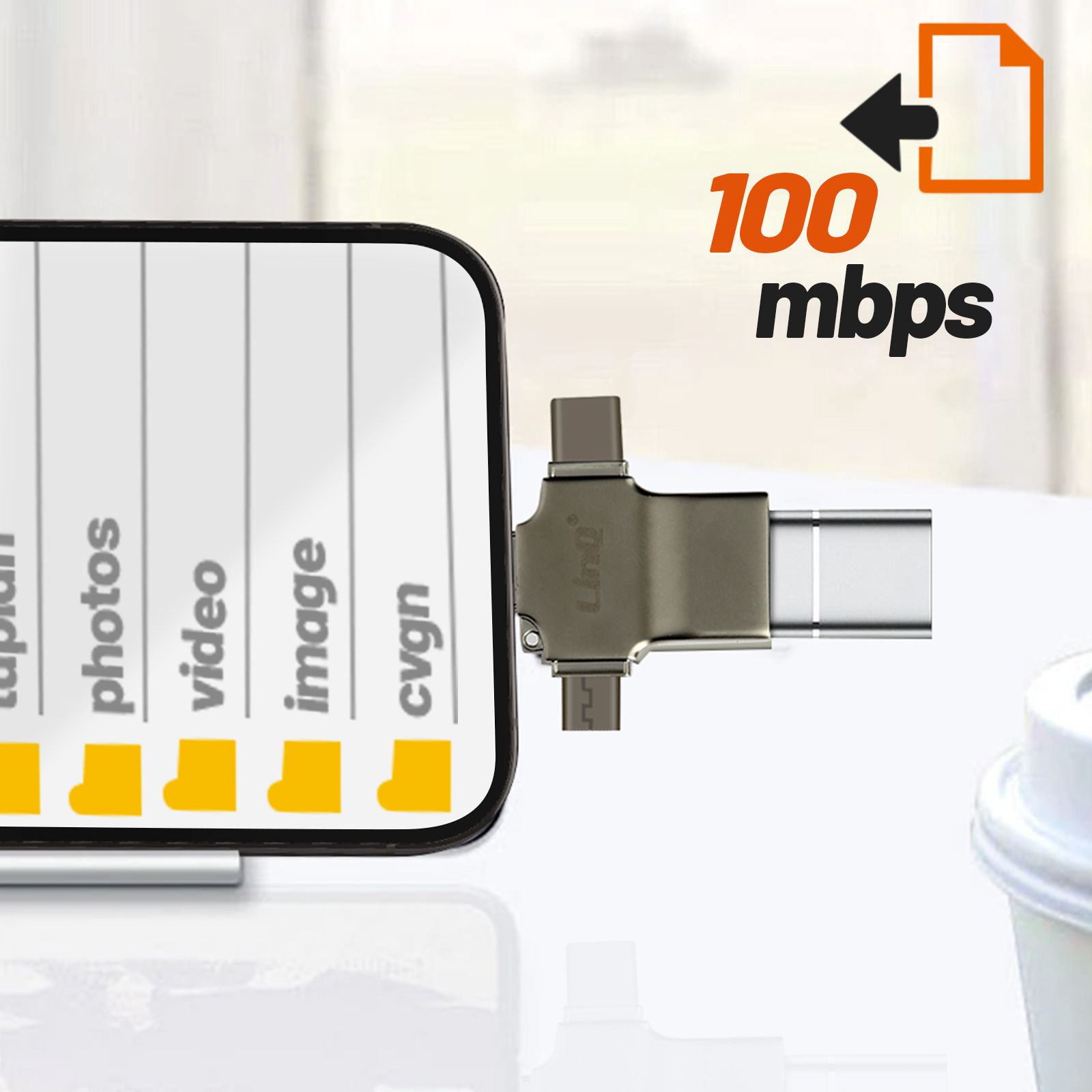 Telefon mit USB-Adapter, zeigt Dateiordner und 100 Mbit/s Übertragungsrate, mit Kaffeetasse.
