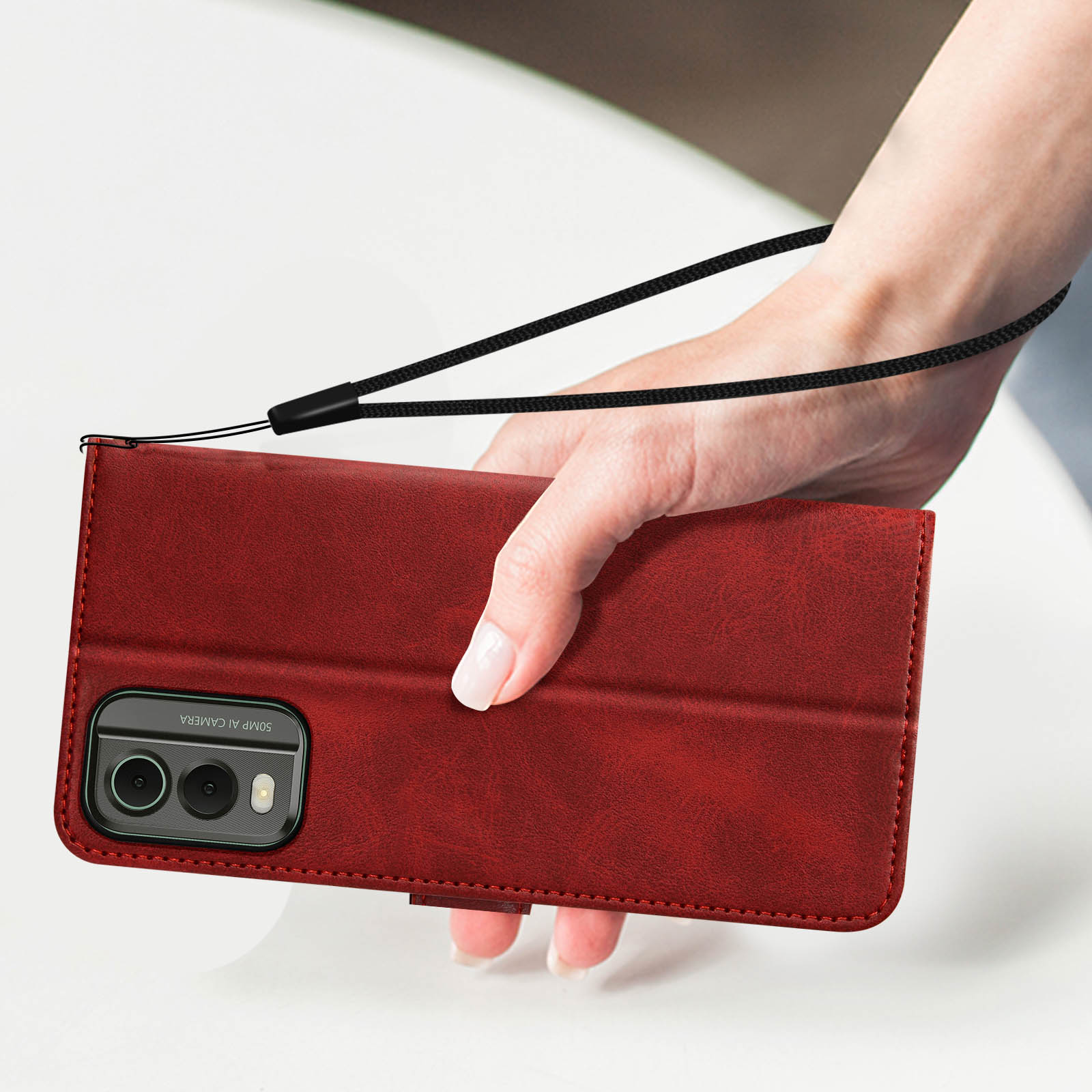 Una mano tiene una custodia rossa per telefono con un cinturino da polso. Il telefono ha due fotocamere.