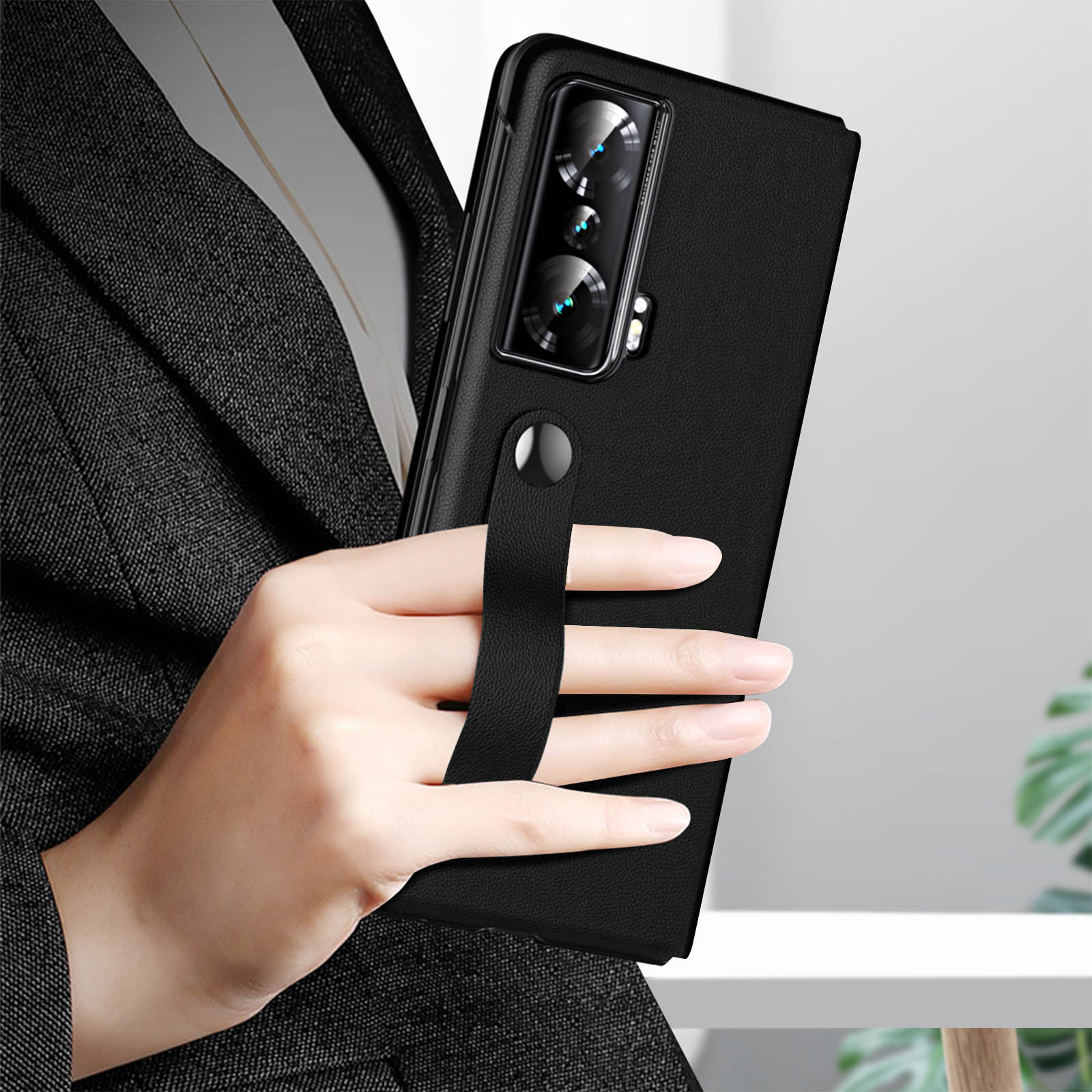 Un telefono in una custodia nera tenuto da una persona. Il telefono ha un cinturino.