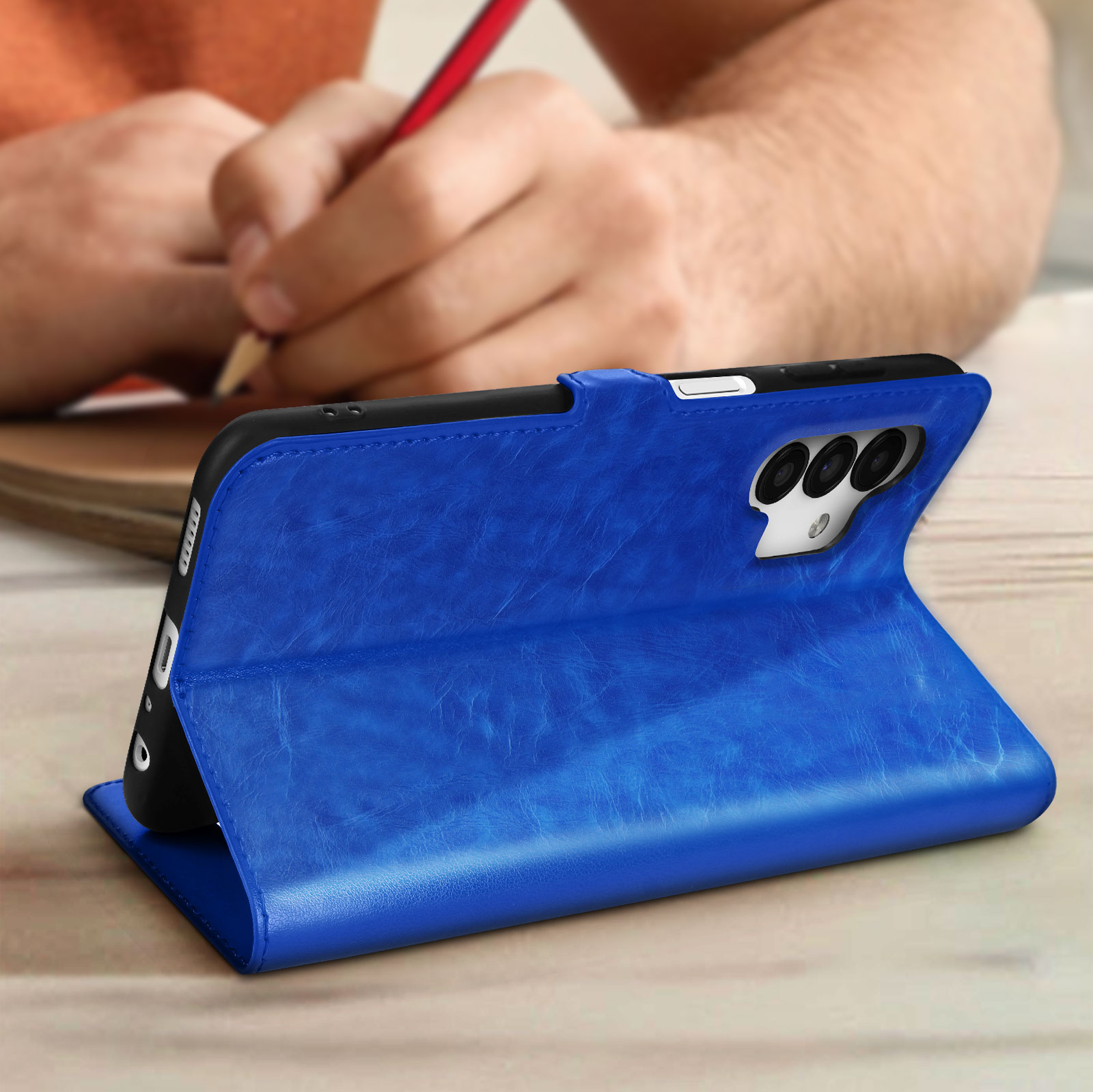 Custodia blu per telefono aperta con un telefono all'interno. Persona che disegna sullo sfondo.