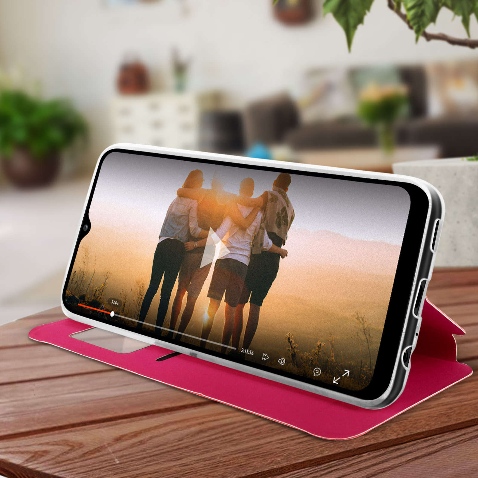 Un telefono su un tavolo di legno mostra un video, la custodia è rossa.
