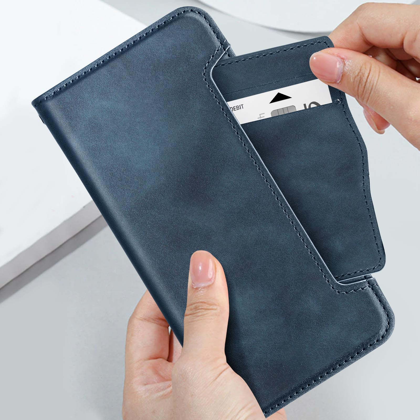 Una mano apre una custodia blu per telefono, rivelando uno slot per schede. Una carta di debito è parzialmente visibile.