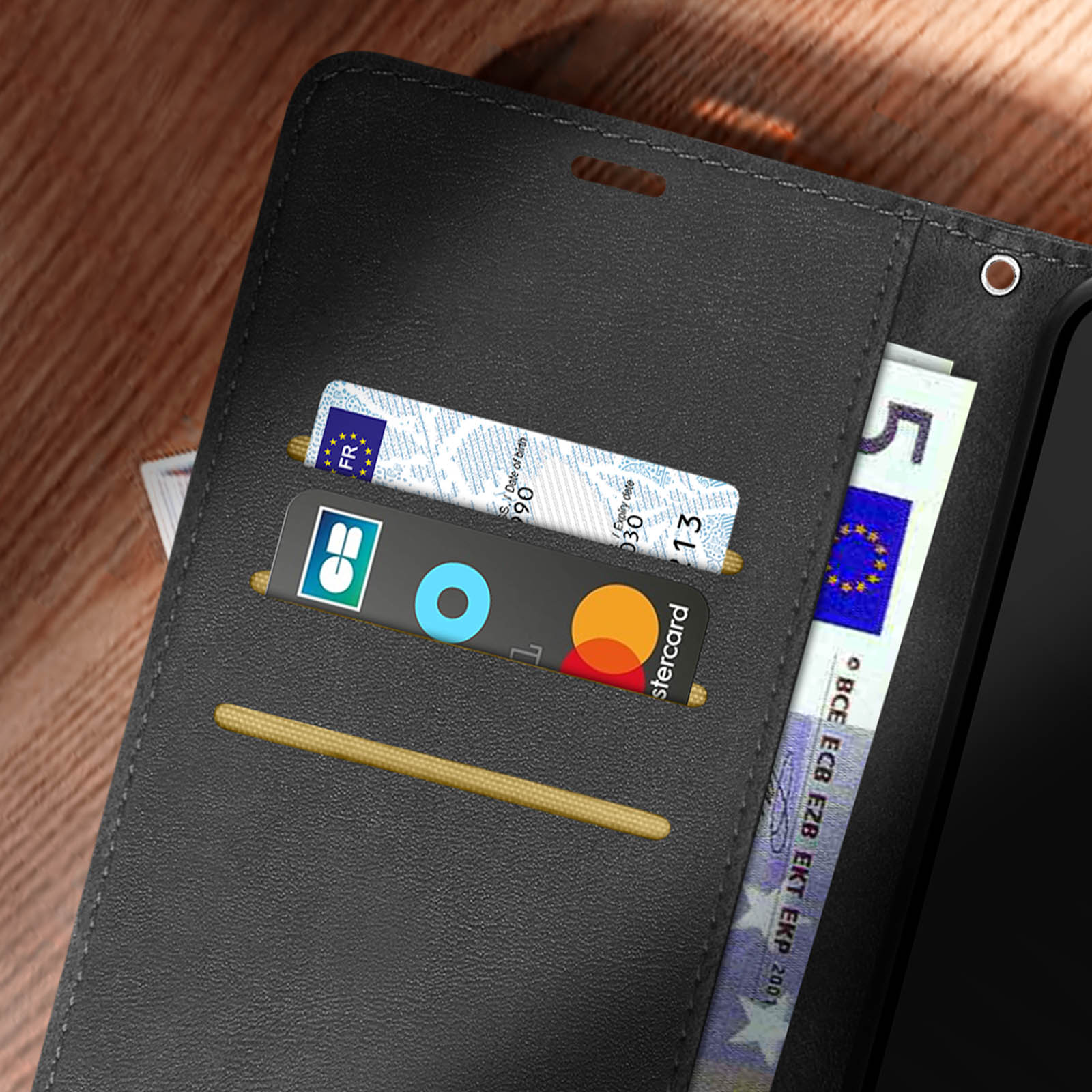 Un telefono, carte di credito e un foglio di carta sono all'interno di una custodia per telefono nera.