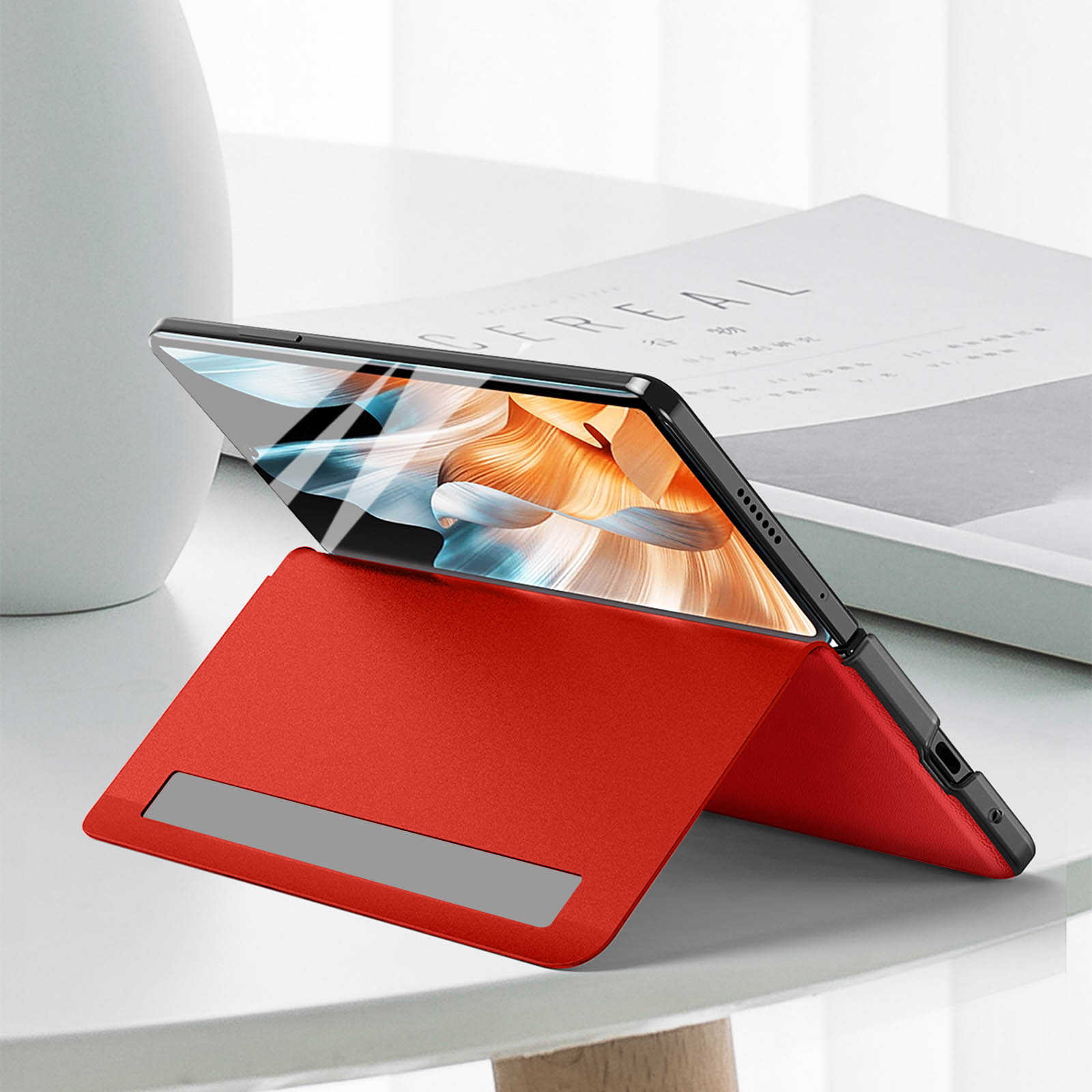 Custodia per tablet rossa con un tablet all'interno, in posizione verticale, su un tavolo bianco.