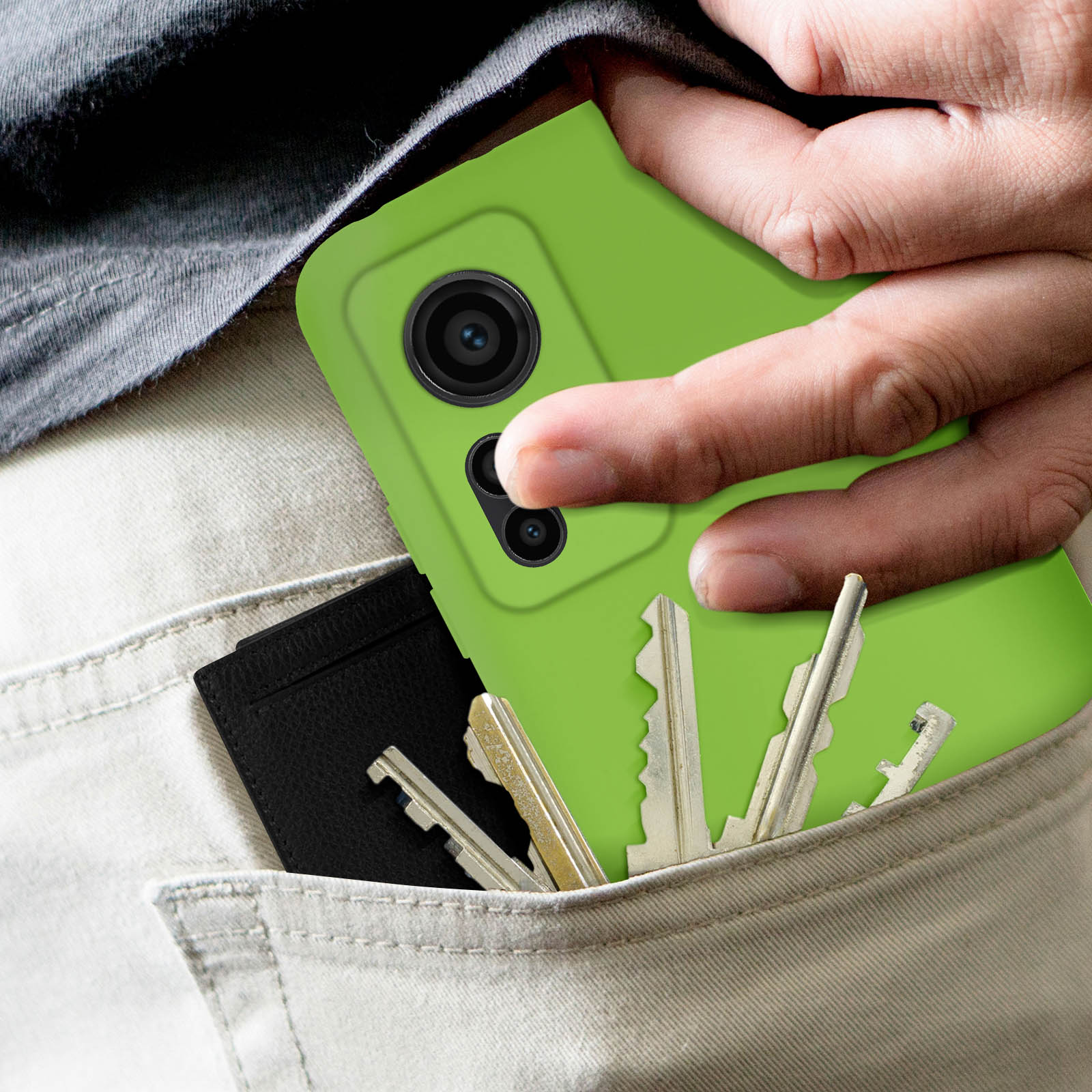 Mano in tasca che tiene una custodia verde per telefono, chiavi e un porta carte nero.