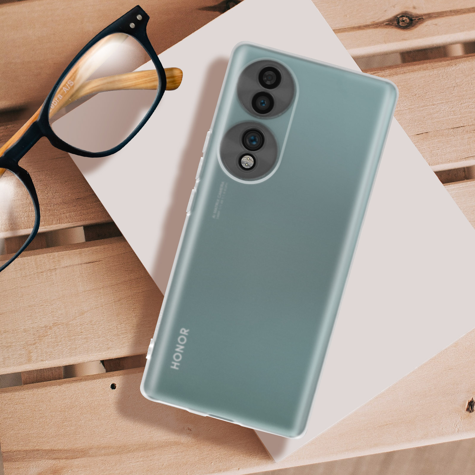 Un telefono su una superficie bianca con occhiali su legno.