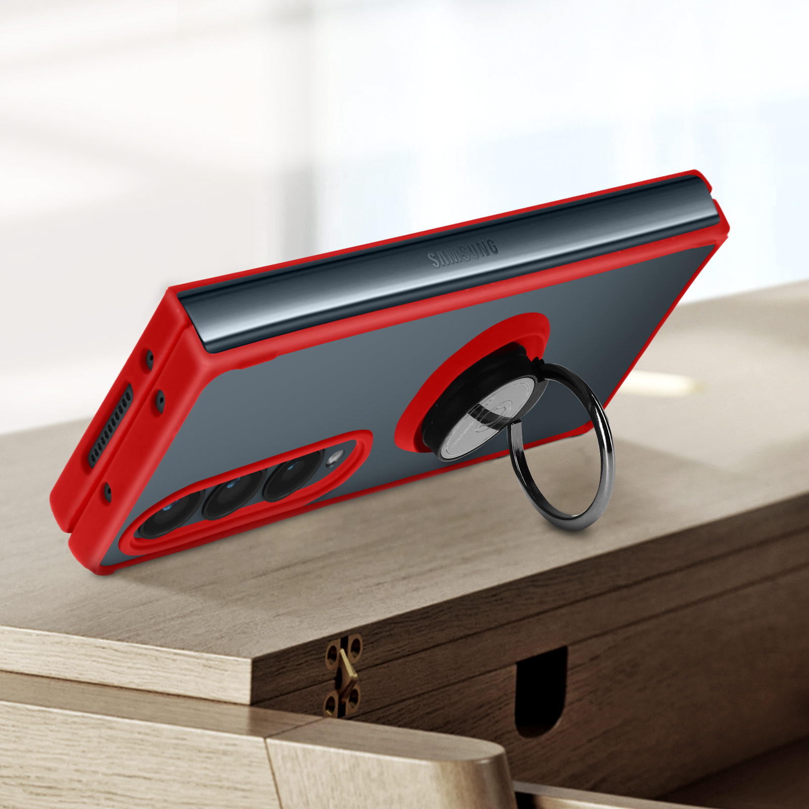 Una custodia per telefono rossa e nera con un supporto ad anello. La custodia è su una superficie di legno. Il telefono è inclinato.