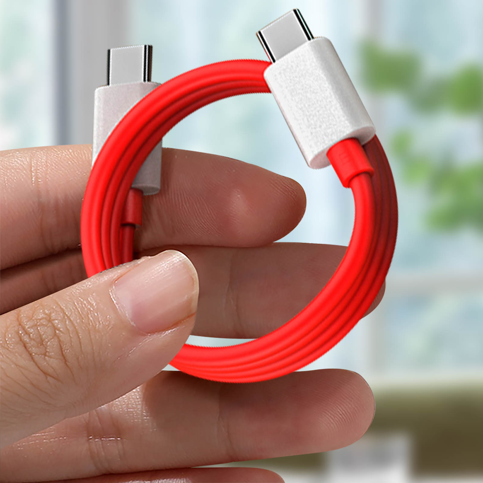 Rotes und weißes USB-C-Kabel. Das Kabel wird von einer Hand gehalten. Weiße Stecker.