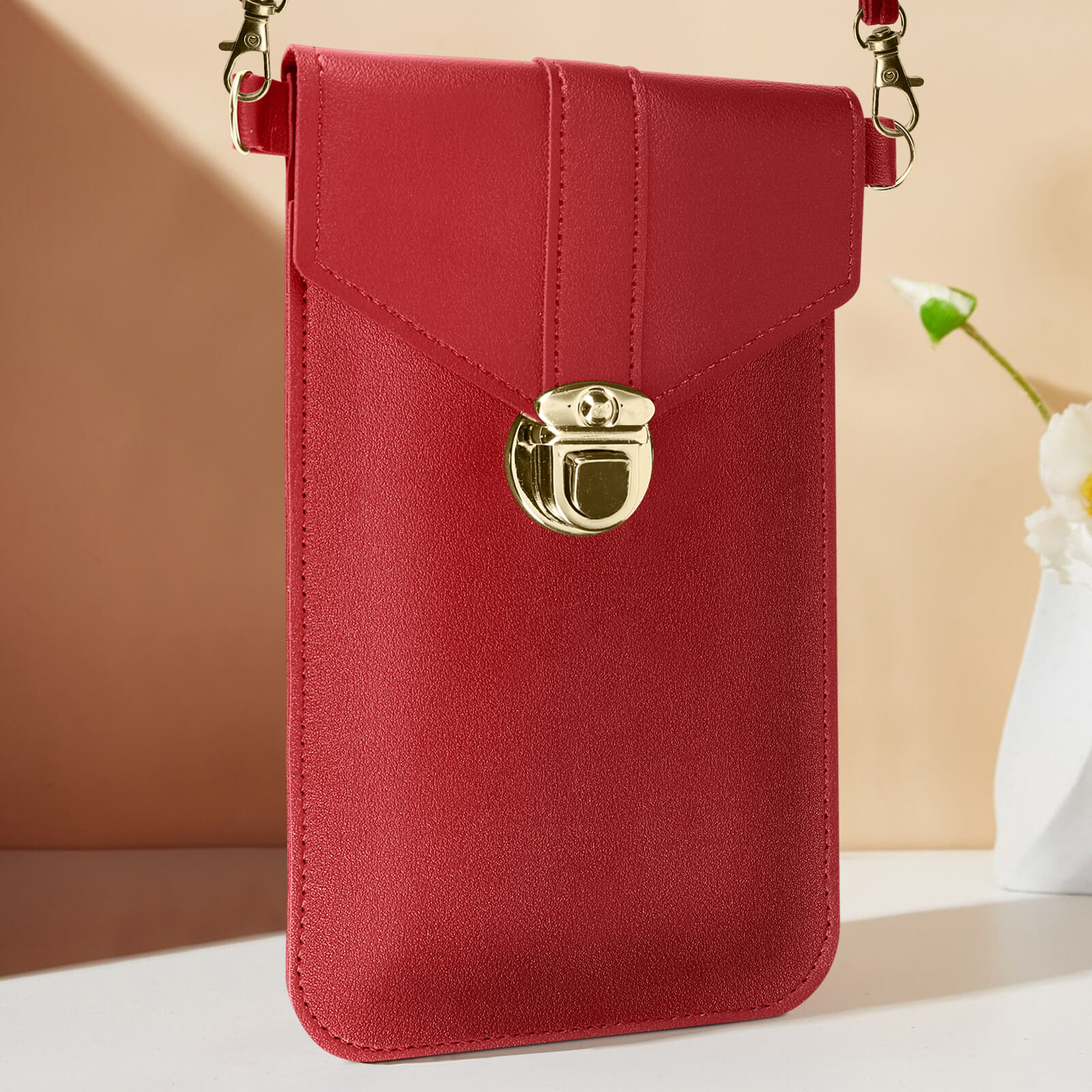 Una custodia rossa in pelle con chiusura dorata e tracolla.