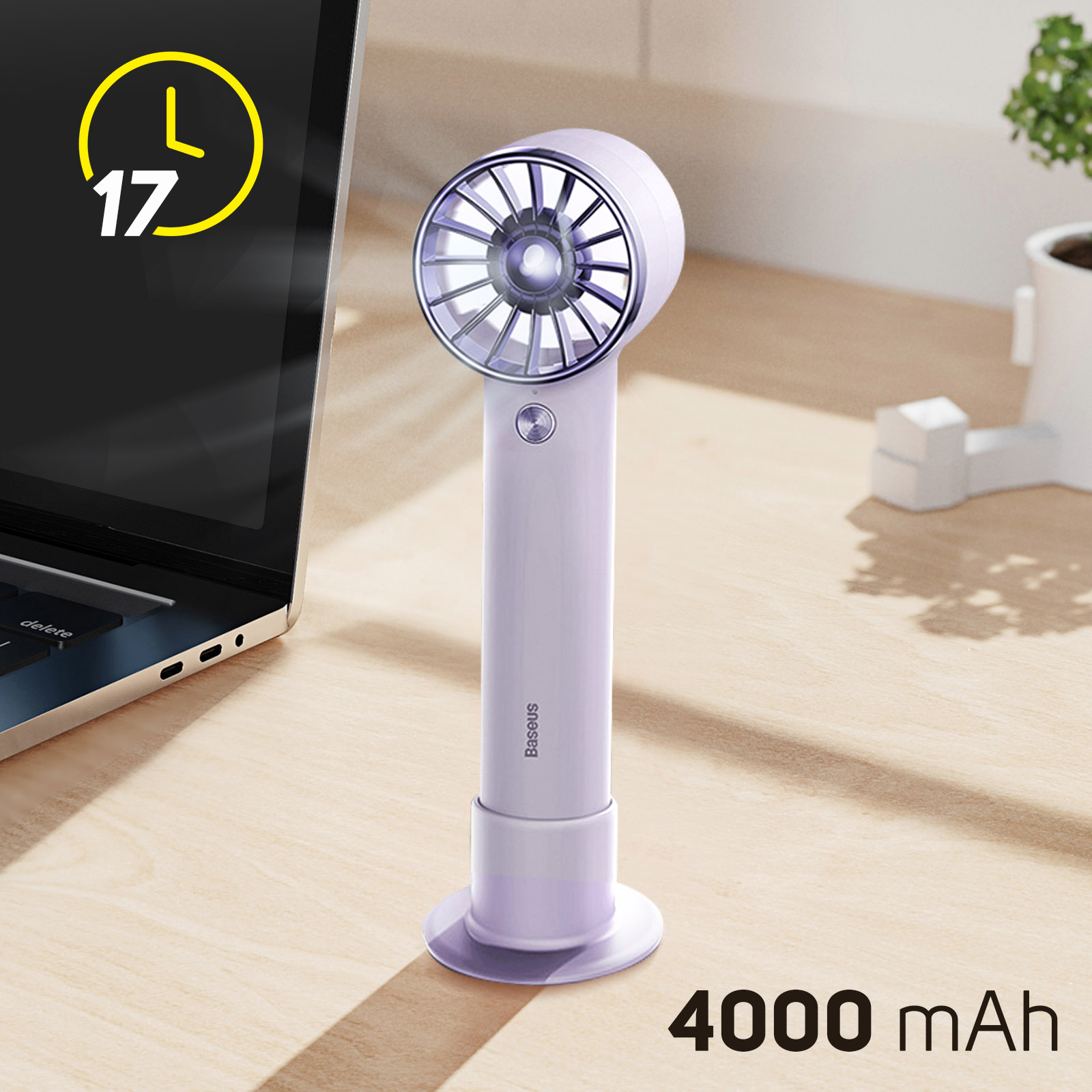 Un ventilador pequeño, blanco y morado con un soporte en un escritorio de madera. Una computadora portátil en el fondo.