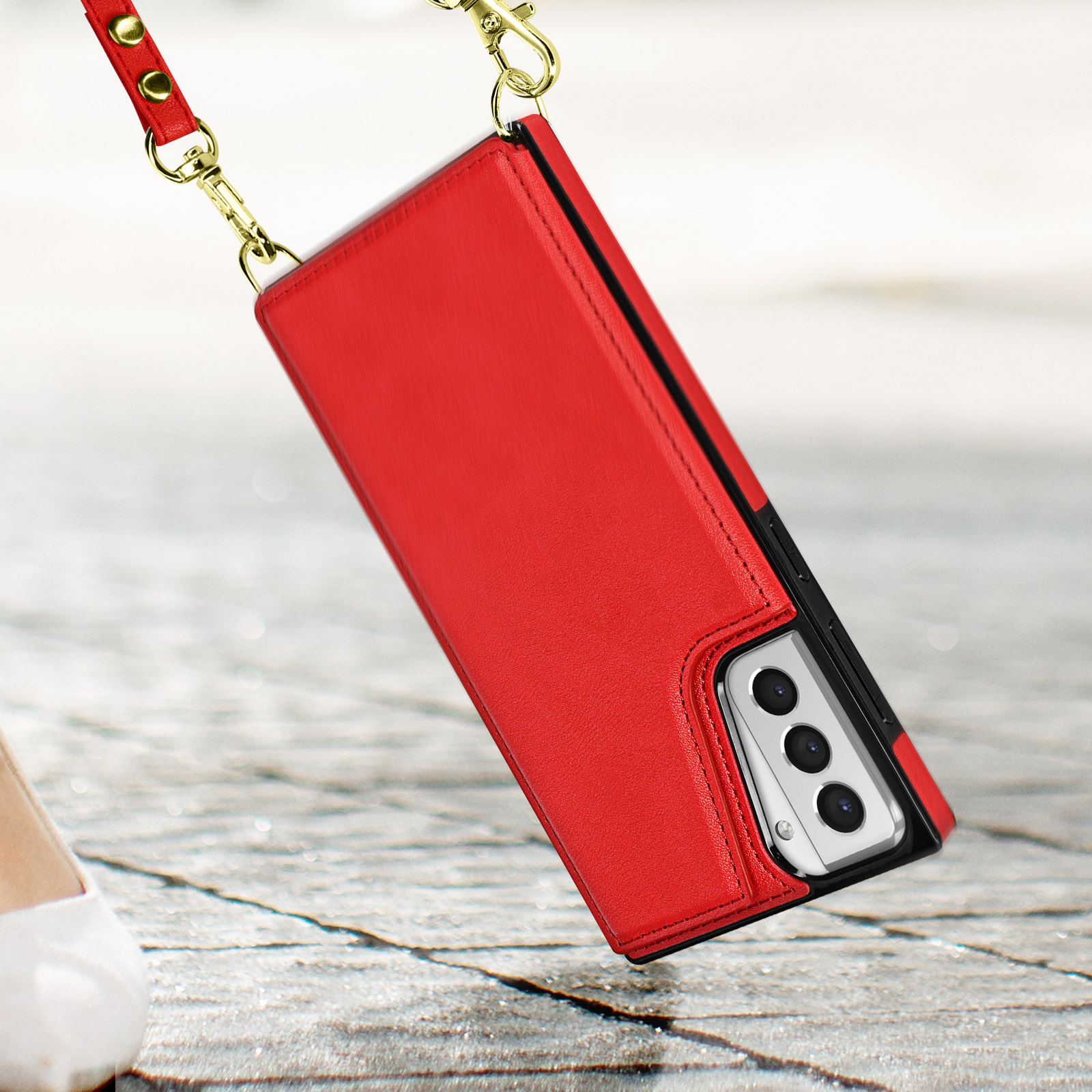 Rote Handyhülle mit Riemen, hält ein Telefon mit Kameras. Der Hintergrund ist ein Bürgersteig.