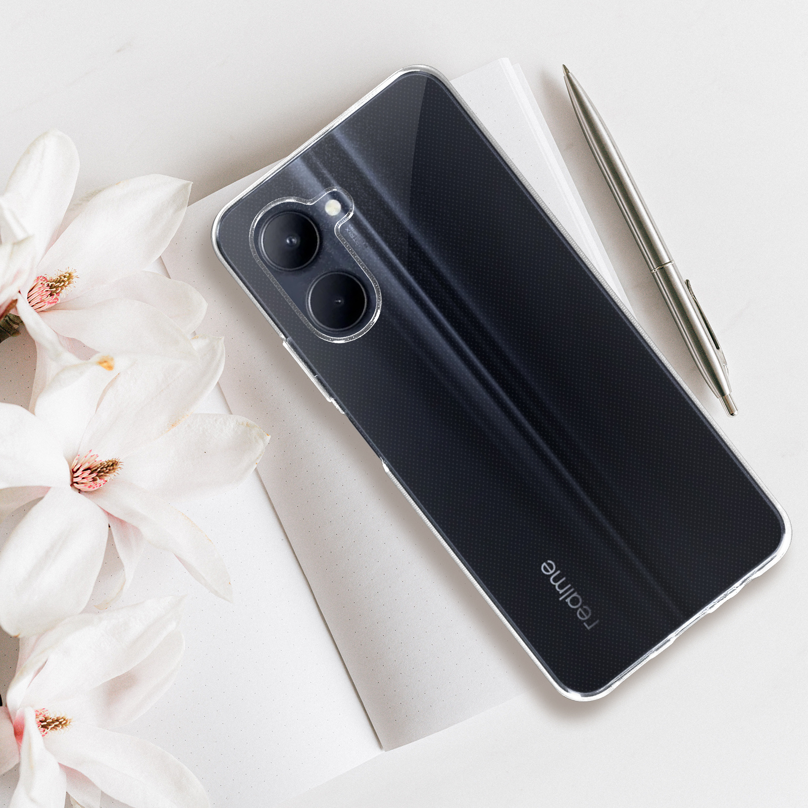 Telefono con custodia trasparente, una penna e fiori su una scrivania.