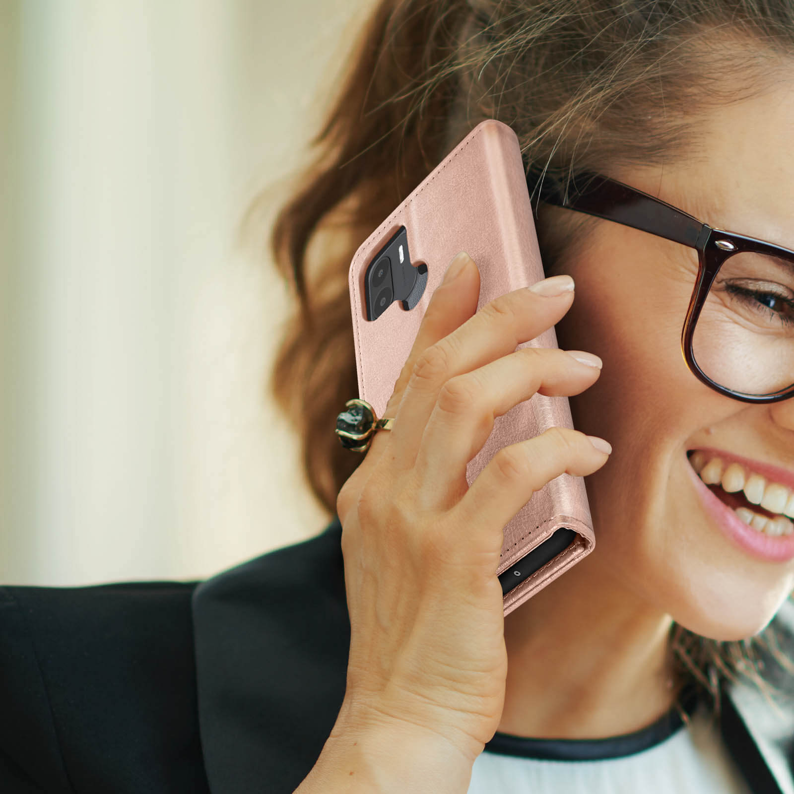 Donna sorridente, parla al telefono con una custodia rosa.