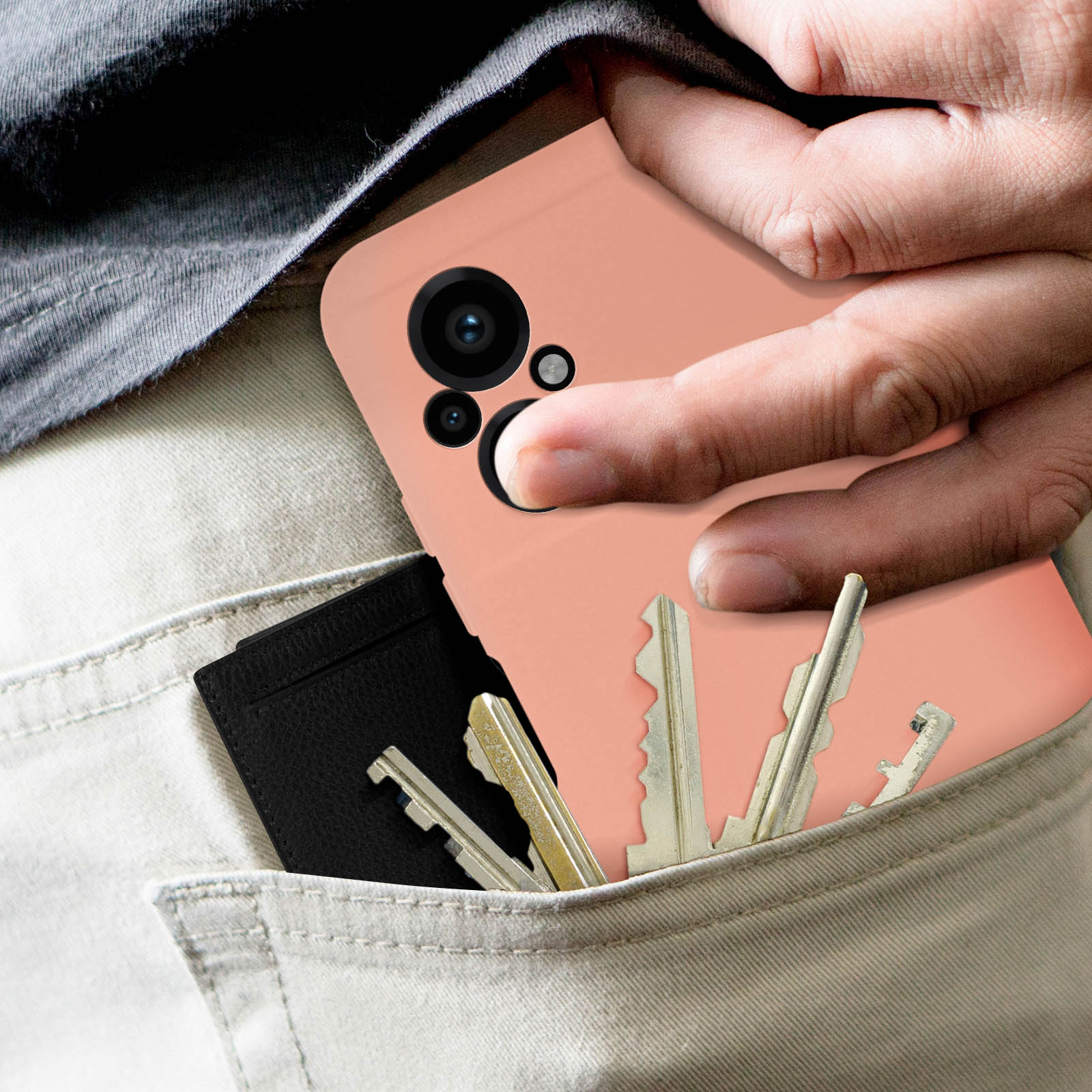 Eine Hand hält ein rosa Telefon mit Schlüsseln und einer Geldbörse in einer Tasche.