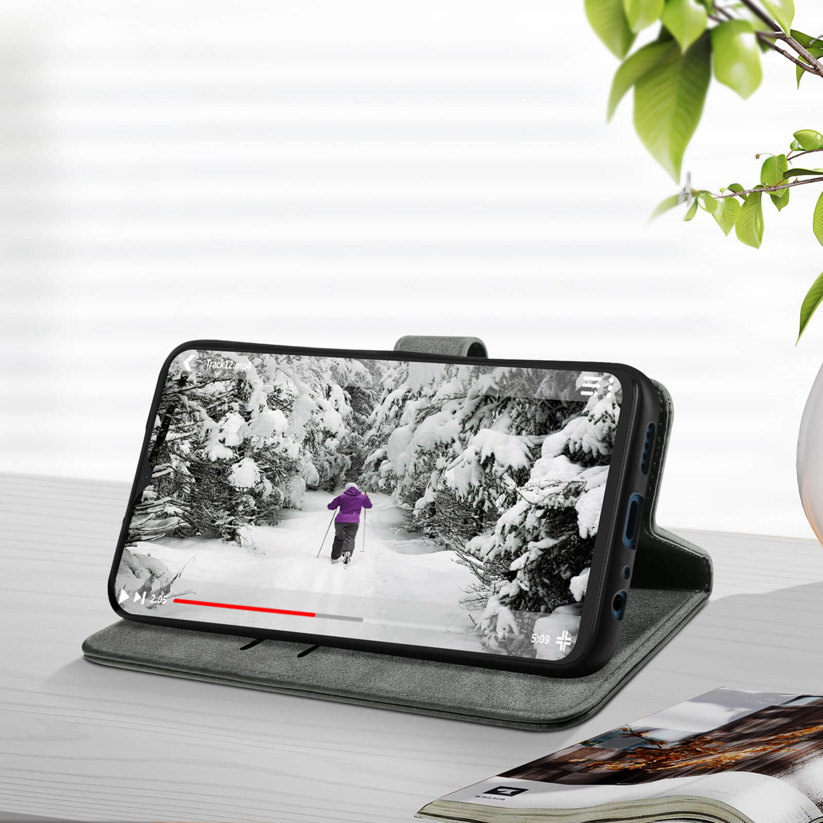 Telefon in Hülle mit Winterszene. Die Hülle ist auf einem Tisch geöffnet. Verschwommener Hintergrund.